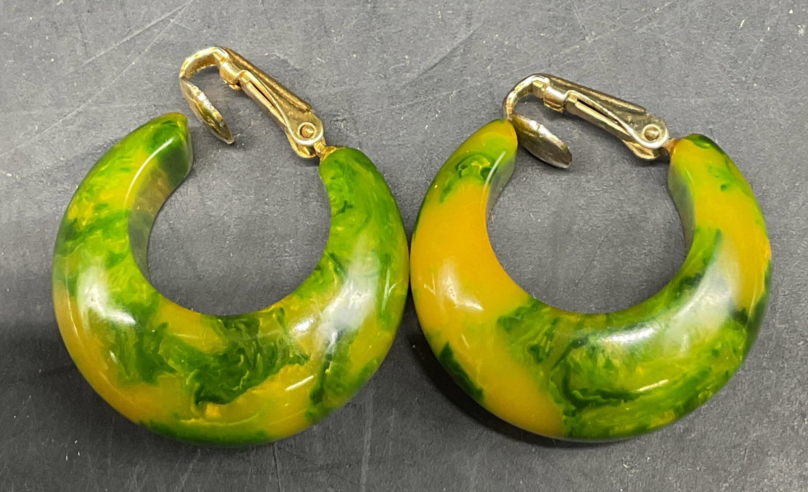 Vintage Bakelite Green Hoop Clip On Earrings: Vintage Bakelite green hoop clip on earrings. Green and yellow marbled gradient. Gold toned closure. Measures approx 1 inch in diameter. Scratching. Jewelry, earrings, estate jewelry, costume
