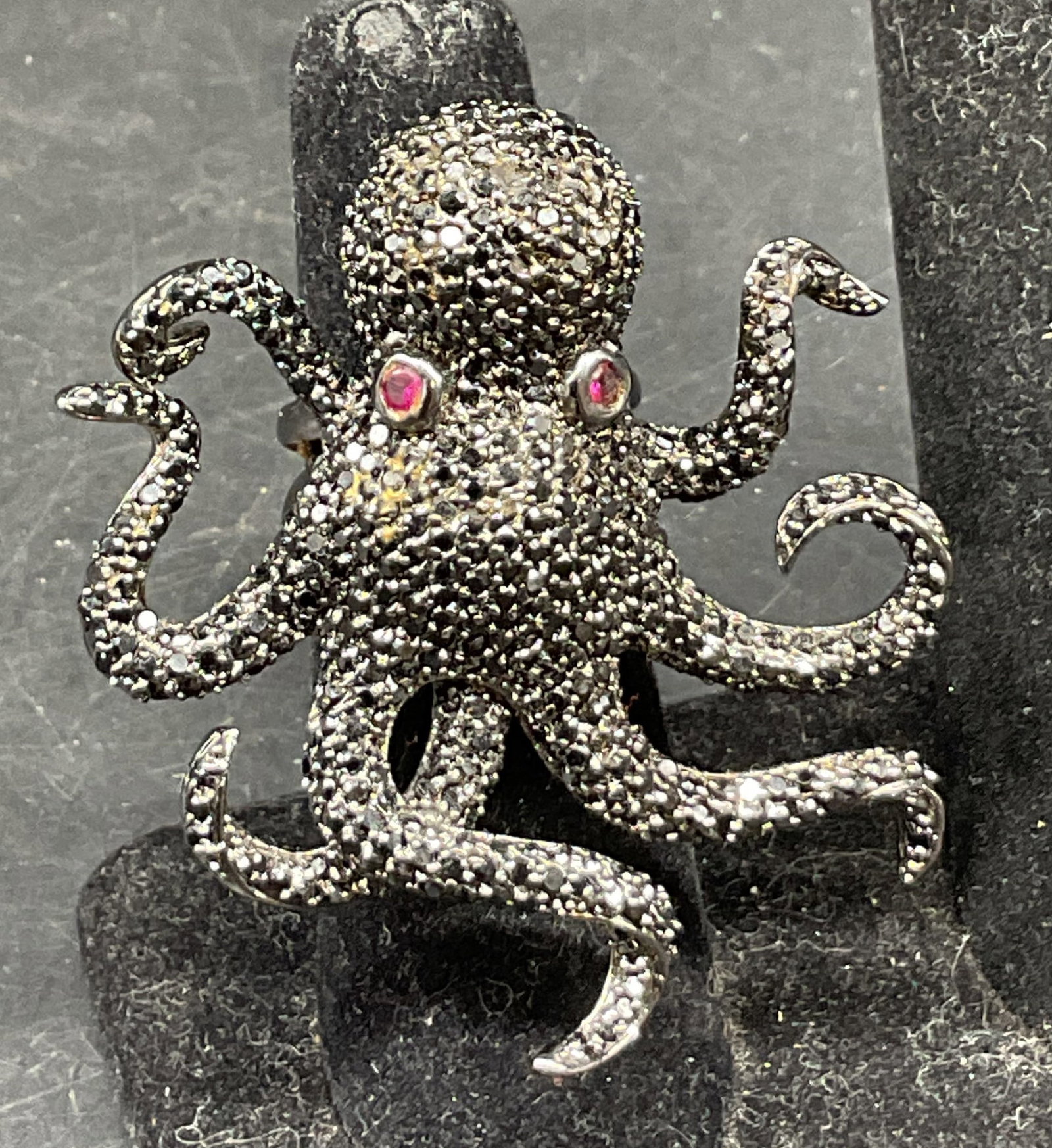 Vintage NOir Black Octopus Statement Ring: Vintage nOir black octopus statement ring. Surface is marked nOir CN. Silver toned band. Octopus figure with black rhinestones and red semiprecious gemstone eyes. Tested with Presidium Gem Tester II. 