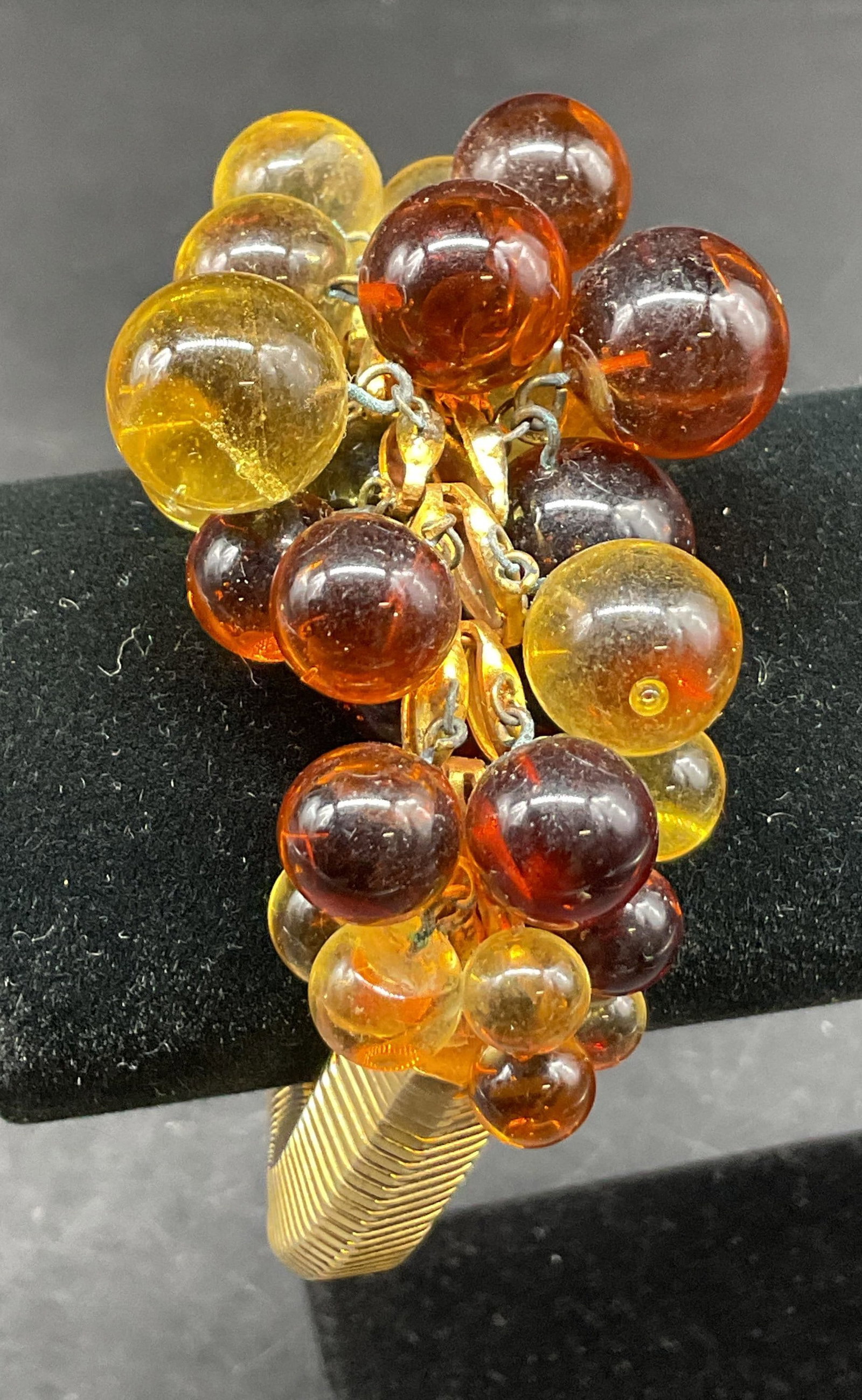 Vintage Gold Toned Amber Cluster Bracelet: Vintage gold toned amber cluster bracelet. Textured gold toned band. Cluster of amber and yellow colored accents. Measures approx 8 inches full length. Scratching. Jewelry, bracelet, estate jewelry, c