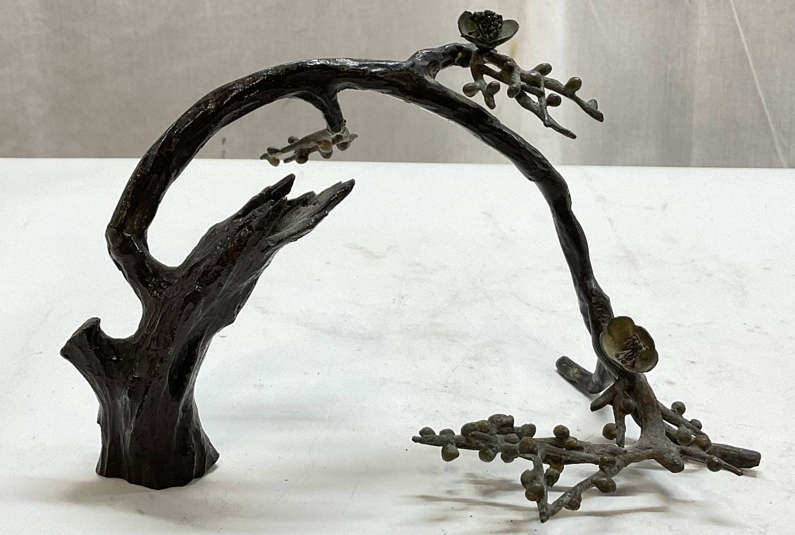 Vtg Patinated Bronze Decorative Branch Sculpture: Vintage patinated bronze decorative branch sculpture. Thick gnarled tree trunk base that curves upward in an arch. Splits into finer twigs adorned with small flower buds and blossomed flowers. Texture