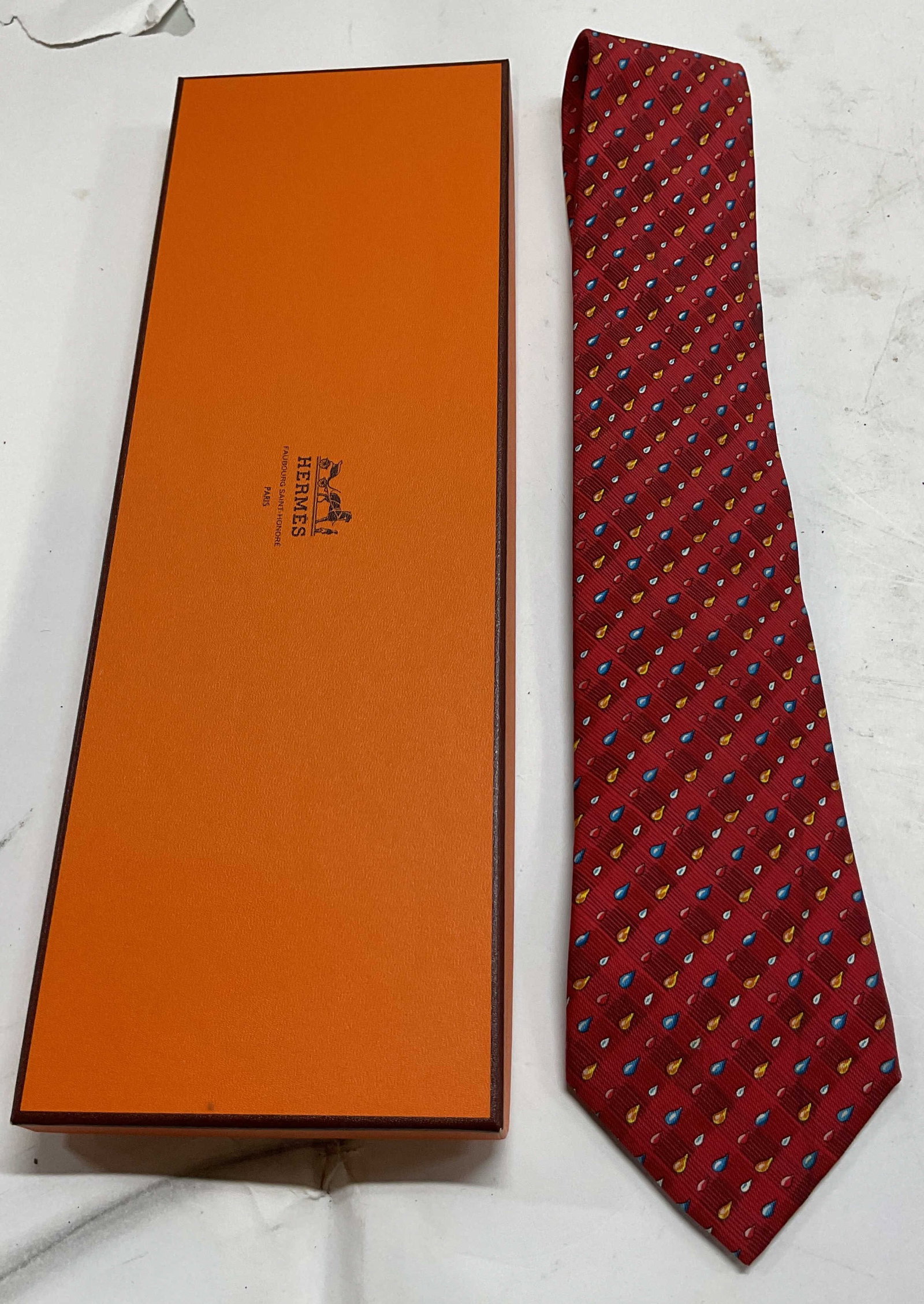 Hermes Red Pattern Silk Neck Tie France W Box: Hermes red pattern silk neck tie. Made in France. 100% silk. Comes with Hermes box. Red checker background with varying colored teardrop pattern. Measures approx 3.5 x 61 inches. Wear consistent with
