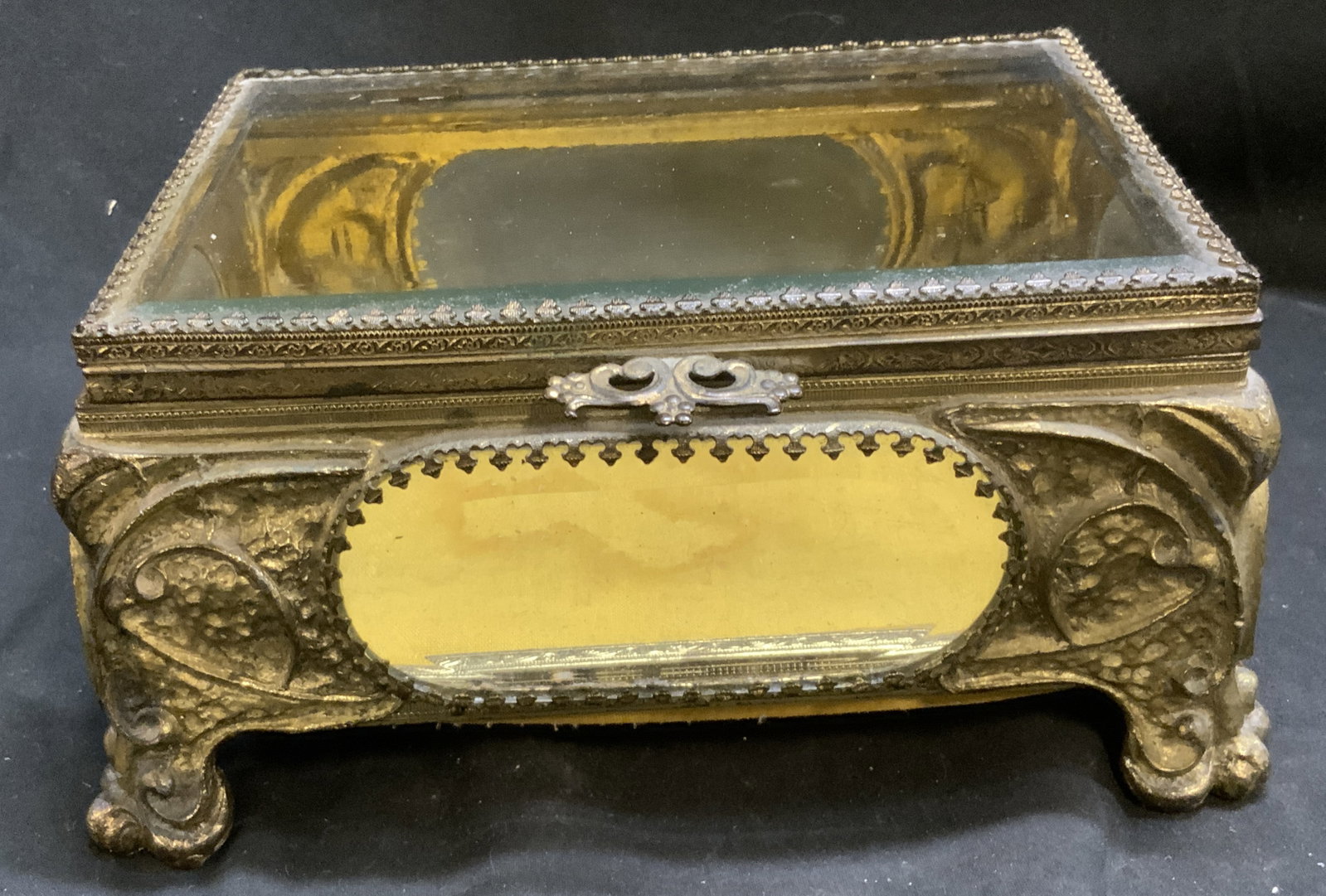 Antique Victorian Cast Brass Jewelry Casket: Antique Victorian Cast Brass Jewelry Casket. Gilt finish. Elaborate scrollwork, acanthus leaf feet, and decorative framing accents. Beveling glass panels. Staining on inside cushion. Some finish loss.