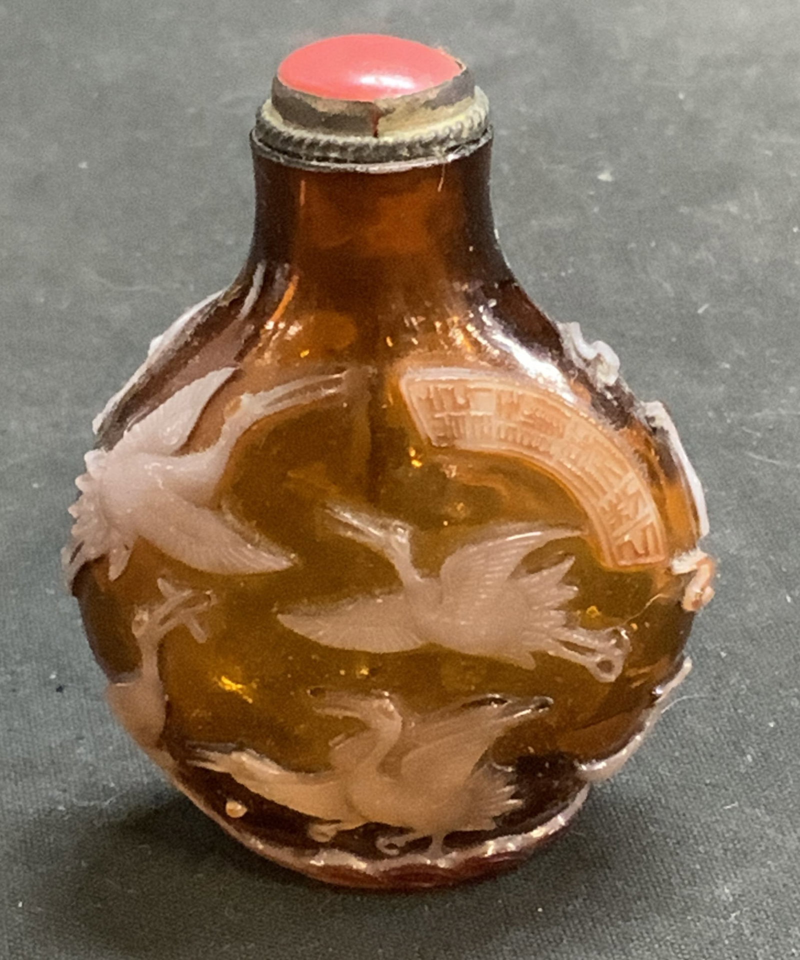 Chinese Peking Glass Crane Motif Snuff Bottle: Antique, Possibly Vintage Chinese Peking Glass Snuff Bottle. carved overlay of white crane motifs. Domed red glass stopper. Condition consistent with age and exposure. Measures app 2.25in H x 1.5in Di