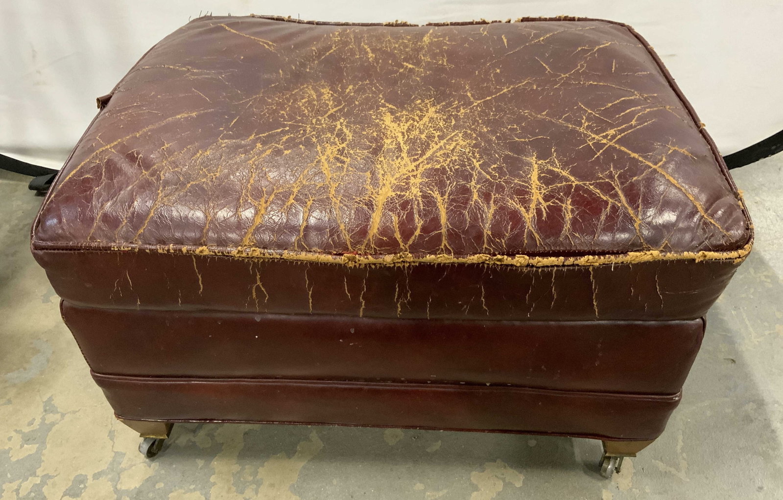 Antique worn Maroon Leather Hassock: Antique possibly vintage worn maroon leather hassock, foot stool, bench, foot rest on casters, measures ht app 15 inches, top app 25 by 18 inches, Wood feet, brass casters
