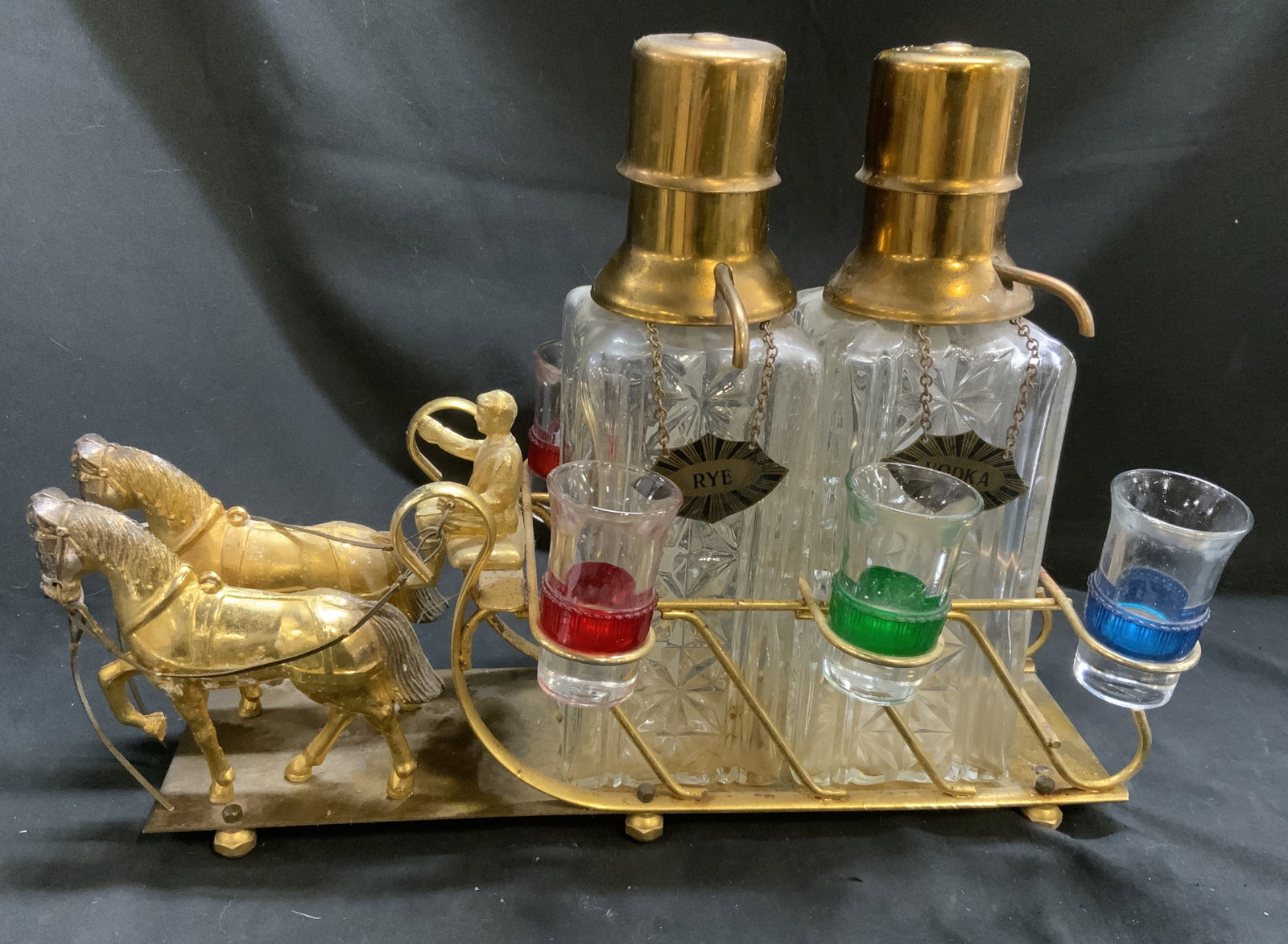 Vtg Brass Horse-And-Carriage Decanter Bar Caddy: Vintage Mid-Century Horse-And-Carriage Decanter Bar Caddy. Gilt brass figurines and horses. Iron stand and body. Molded clear glass bottles with diamond-cut pattern. Gilt brass pump-style dispenser to