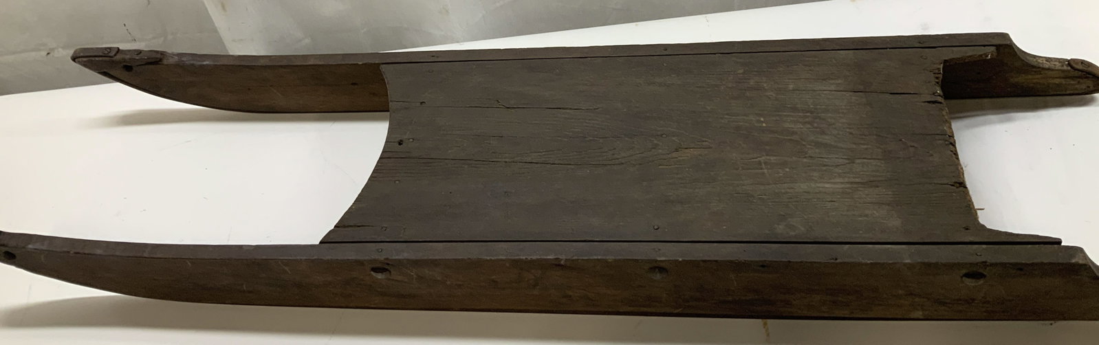 Antique hand built wooden runner sled: Antique hand built wooden runner sled. Aged hardwood planks with an old dark finish and extended curved side runners. Simple joinery with visible nail construction characteristic of domestic making.