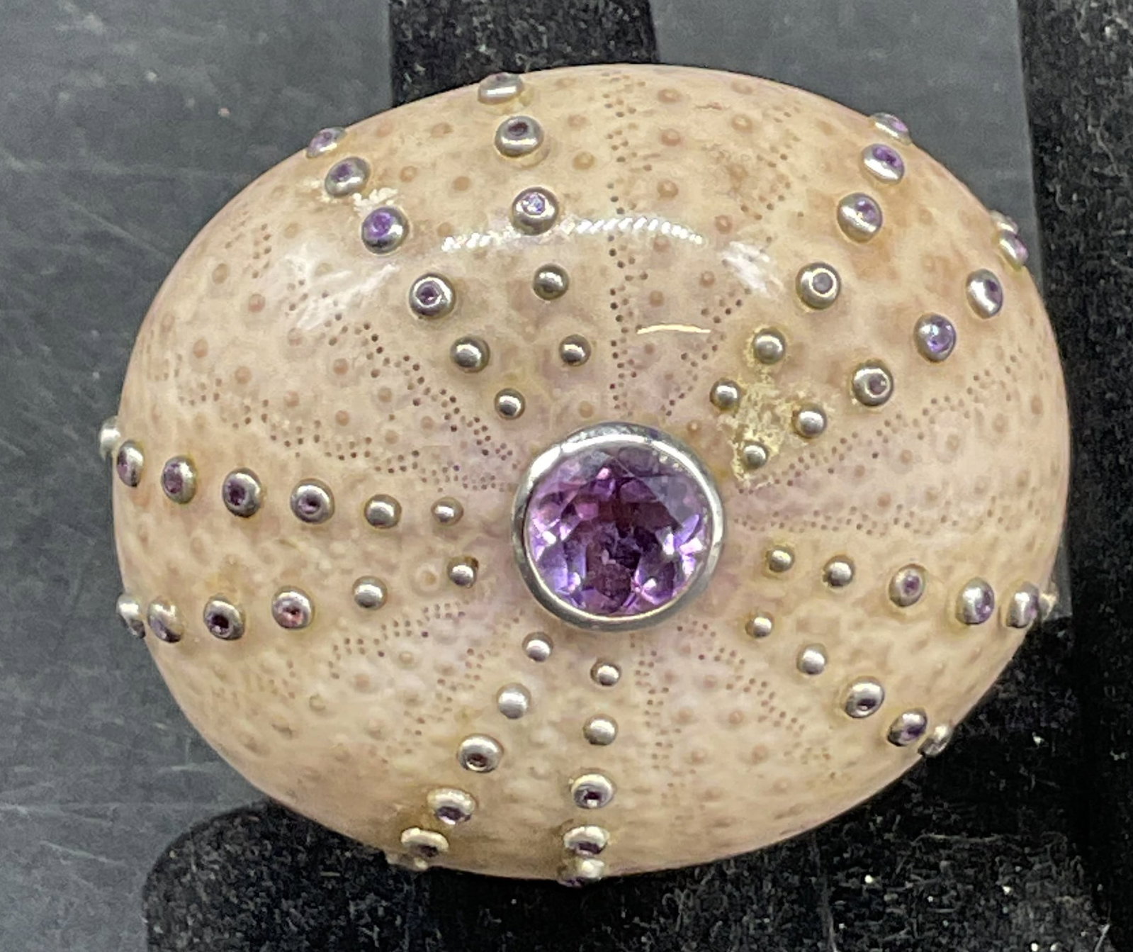 Vtg Sterling Silver Shell & Amethyst Ring: Vintage sterling silver shell and amethyst ring. Surface marked 925. Central cream colored shell embellished with amethyst gemstones and studs. Detailed features. Swirl design on band. Total weight