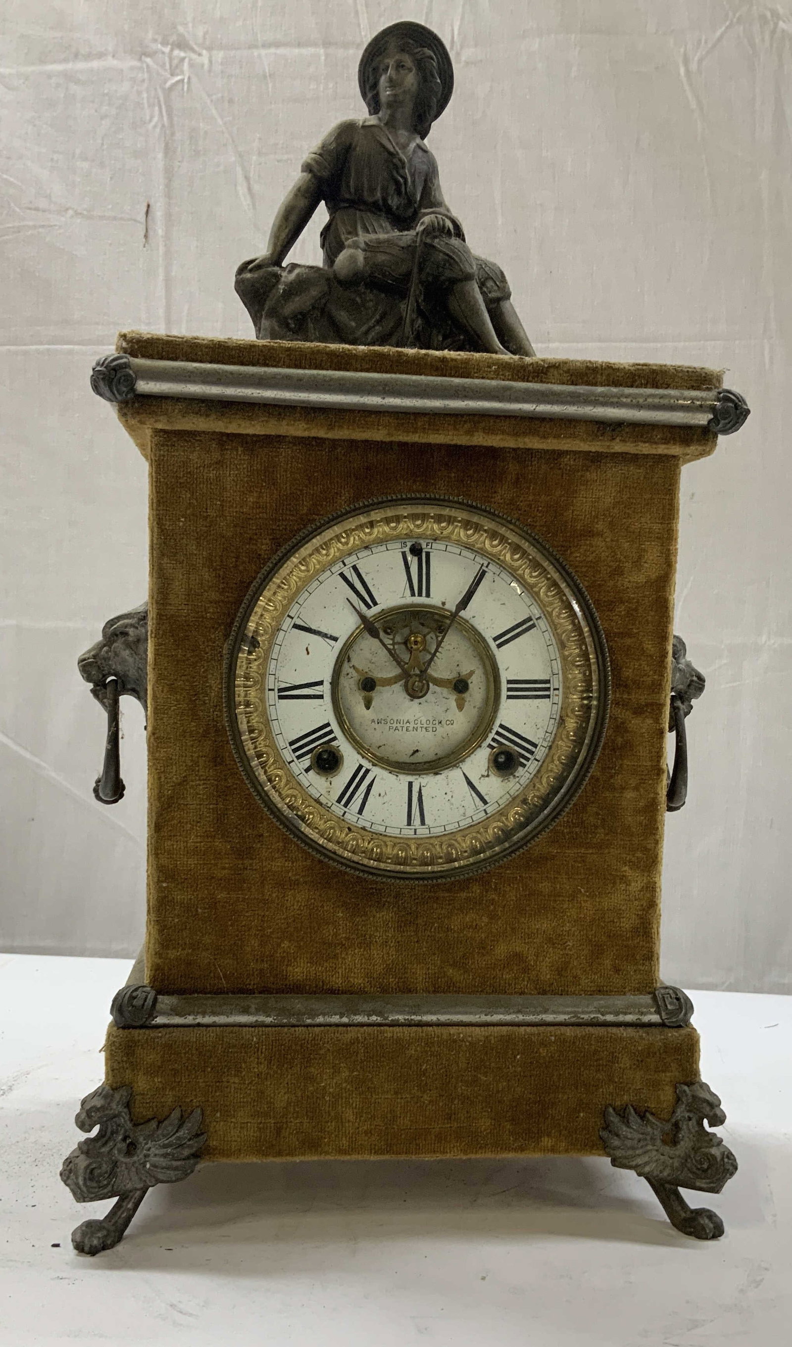 Vntg ANSONIA CLOCK CO. velvet mantel clock: Vintage ANSONIA CLOCK CO. velvet mantel clock. Rectangular plush covered body with ornamental metal feet, side animal head handles, and trim. White enamel face with Roman numerals. A sculpted metal