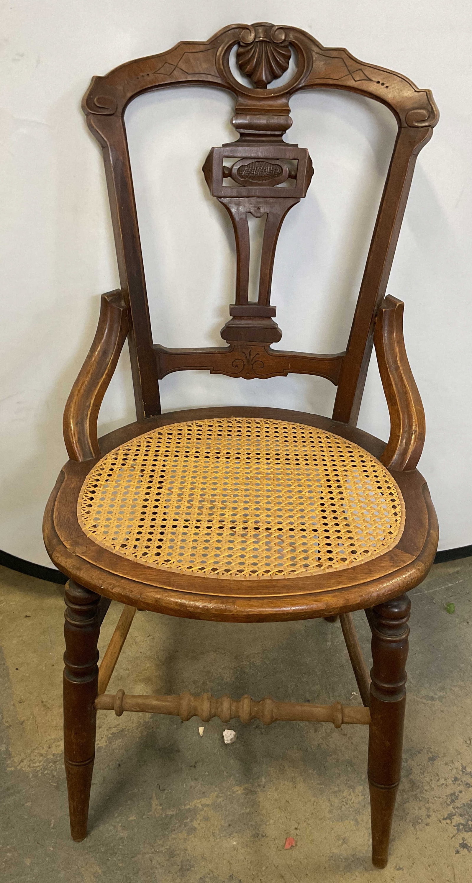 Antique Victorian Style Wooden Cane Parlor Chair: Antique Victorian style wooden cane parlor chair. Carved open frame backrest. Fan motif at the top. Vertical support in the middle splits into a distinct geometric pattern with a raised medallion. Tan