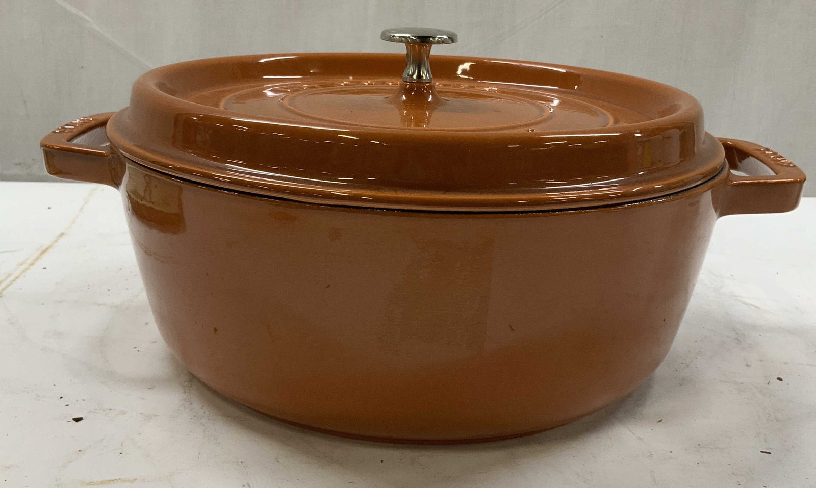 STAUB cast iron orange round pot, France: STAUB large cast iron orange round pot. Made in France . Embossed on the top is STAUB and la cocotte which is French for heavy cast iron cooking pot. In North America it is more commonly referred to