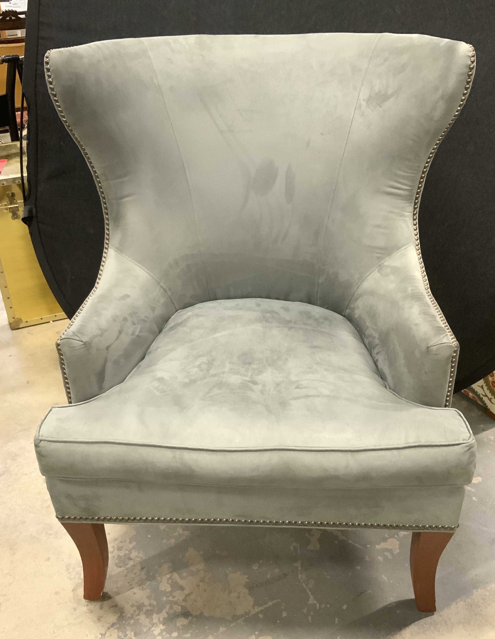 Grange Upholstery Wingback Armchair France: Grange Upholstery Wingback Armchair. High-End furniture maker from France. Grey suede-style material. Flared silhouette. Low cutaway arms. Brass-Toned studded accents. Light staining and scuffing.