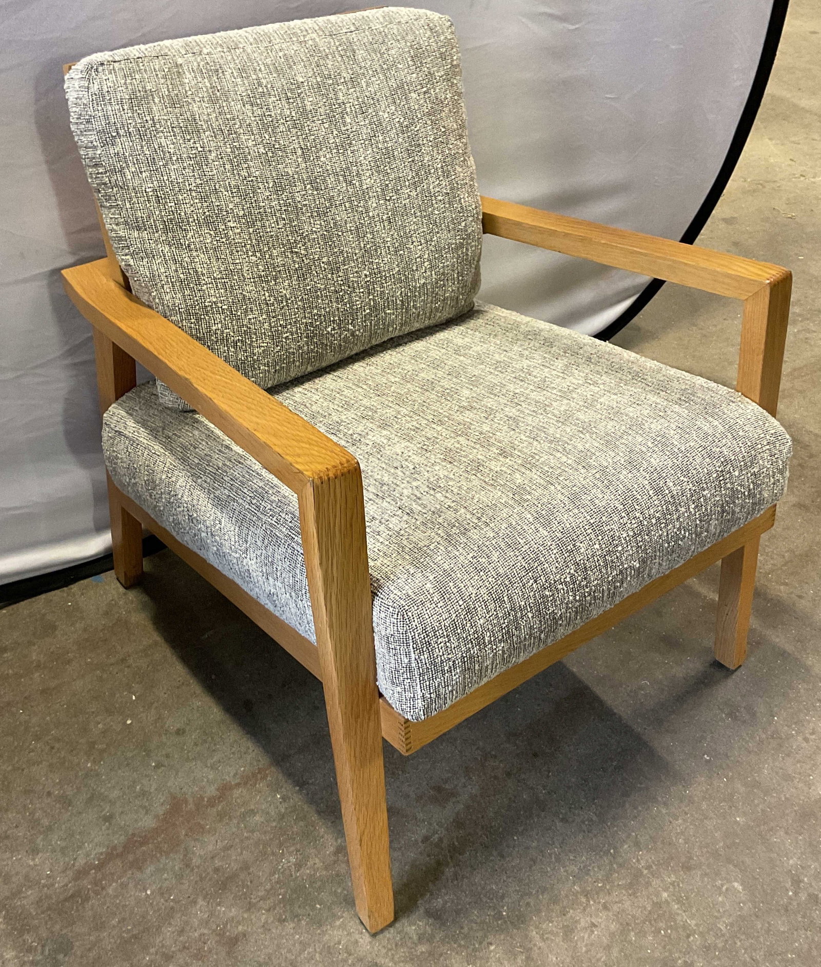 Mid Century Modern Wooden Upholstered Armchair: Mid century modern wooden upholstered armchair. Light toned wooden frame. Shape has square geometric lines, arms run straight and drop down to form flat front legs. Front legs are straight down, back 