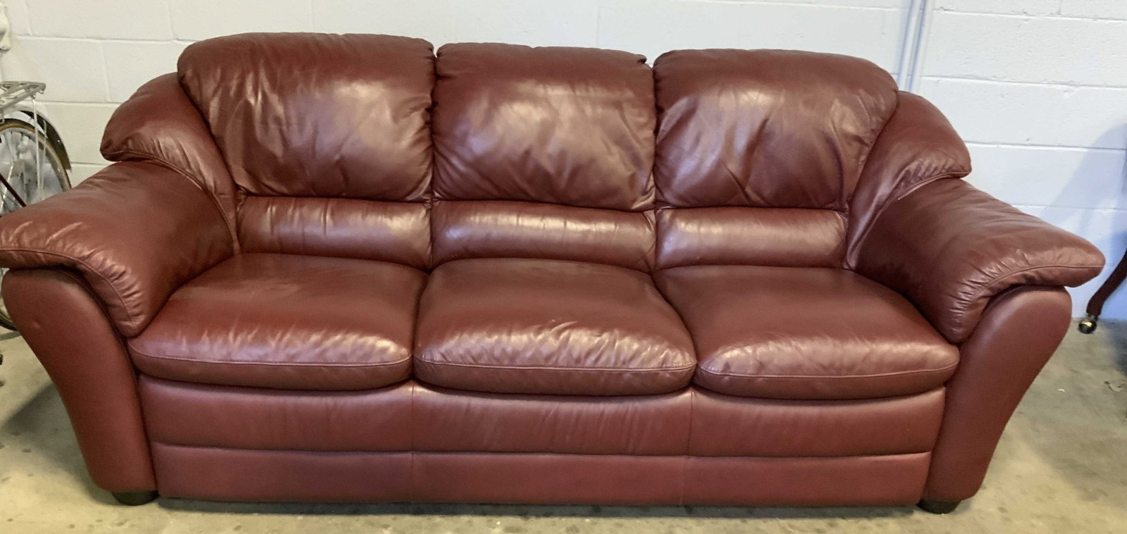 Three Seater Overstuffed Leather Burgandy Sofa: Three seater Burgandy leather over stuffed sofa, Measures ht 37 inches, length 90 inches and depth 37 inches, constructed with thick overstuffed cushions , high pillowed back rest and padded rolled