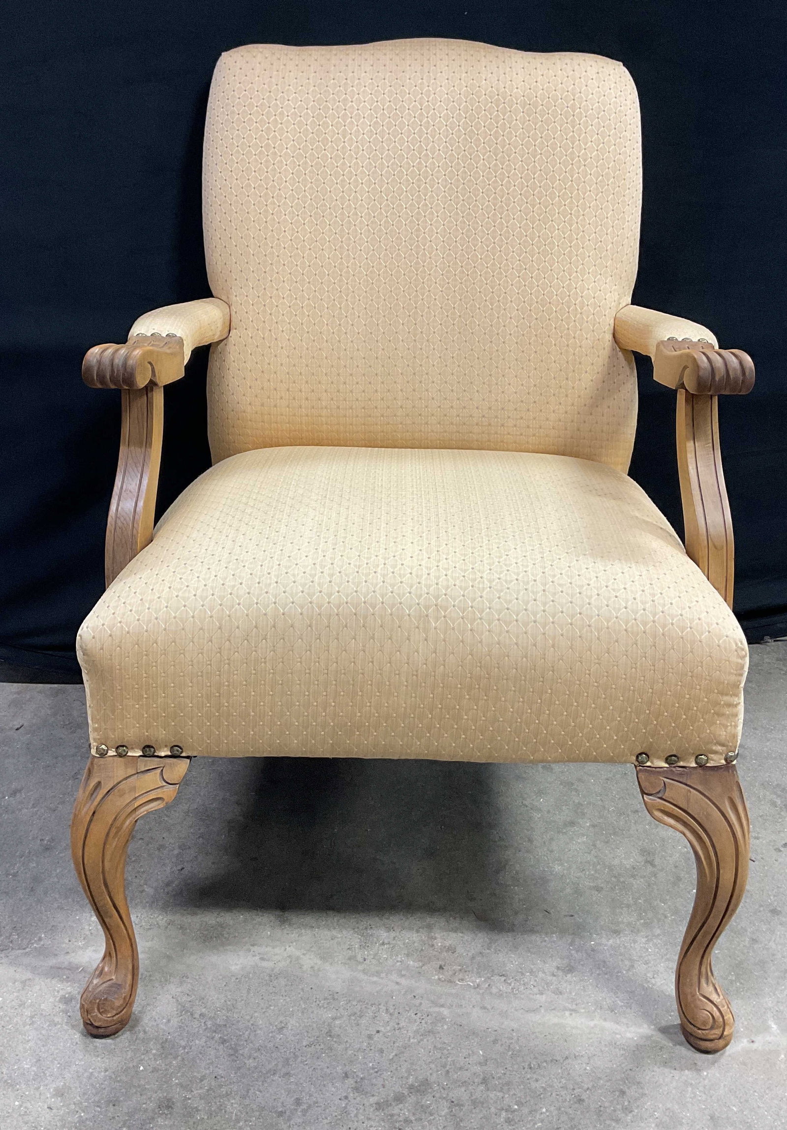 Vintage Queen Anne Style Upholstered Armchair: Vintage Queen Anne style upholstered armchair. Light wooden frame. Upholstered cream colored seat and backrest. Textured diamond pattern. Curved cabriole front legs with carved detailing. Splayed rear
