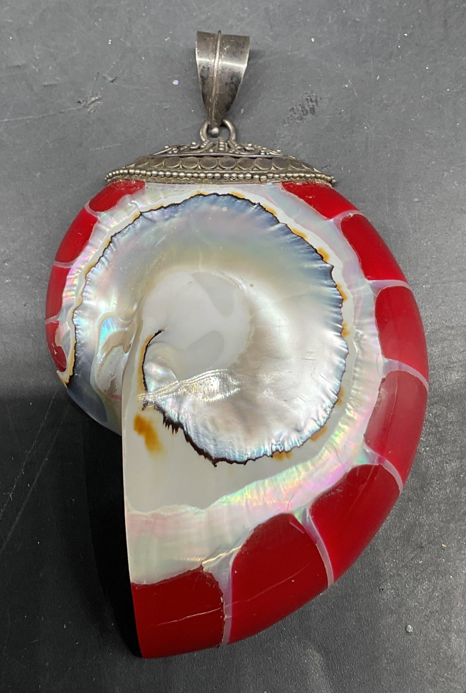 Vtg Sterling Silver Red Nautilus Shell Pendant: Vintage sterling silver red nautilus pearl shell pendant. Surface is marked 925. Iridescent mother of pearl interior. Half cut shell. Outer spiral chambers are filled with red jewelers resin highlight
