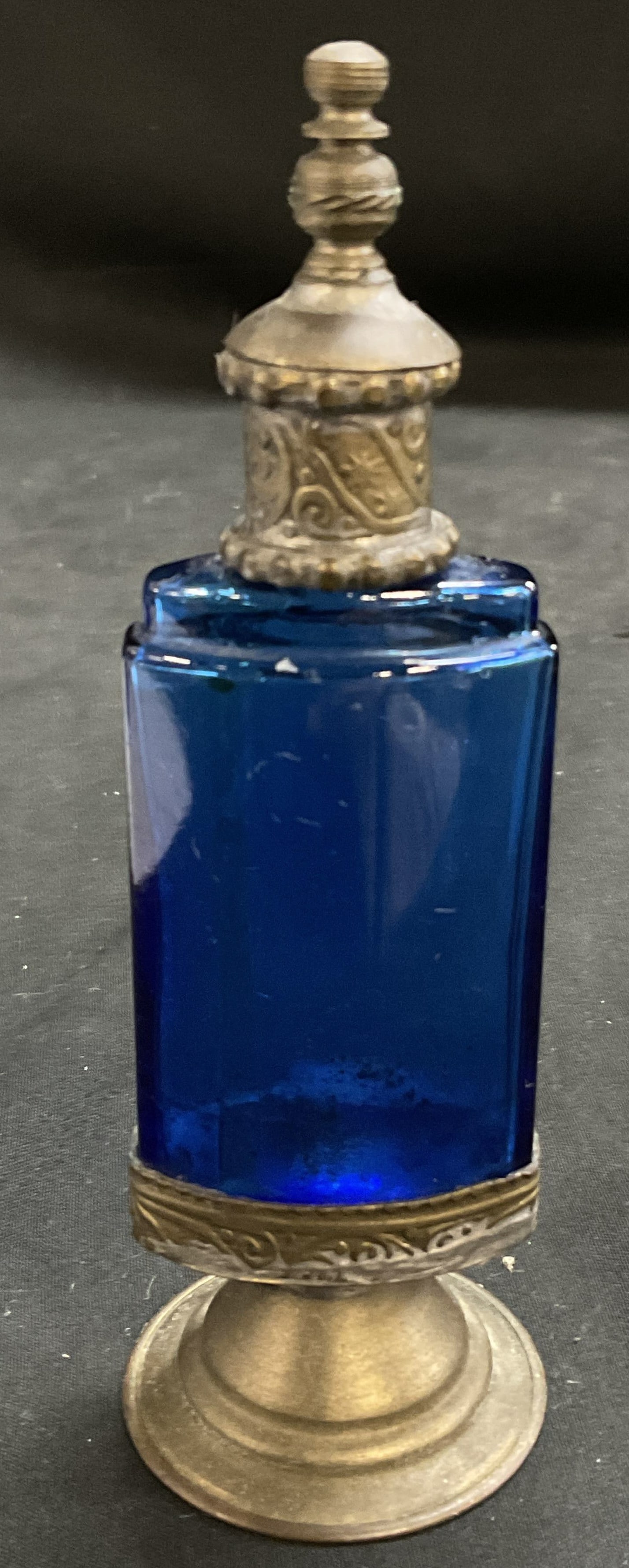 ANTIQUE Cobalt Blue Glass Perfume Bottle: Antique Cobalt Blue Glass Perfume Bottle. Rectangular body with white metal hardware, hinged flip top lid, and pedestal base. Star patterns and scrollwork. Aging to metal and coating loss present. Mea