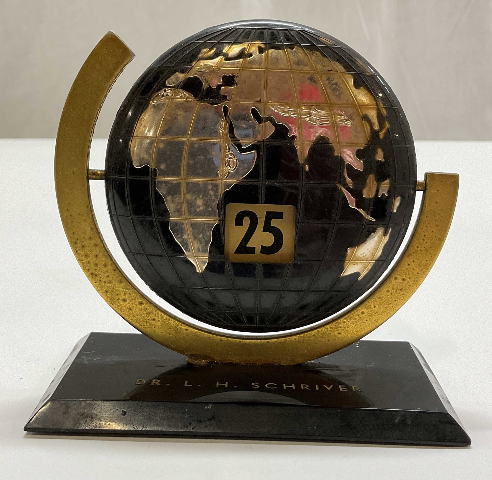 Vtg Bakelite Perpetual Flip Calendar Globe: Vintage Bakelite perpetual flip calendar globe. Rectangular black base, engraving reads Dr L.H. Schriver. Black and gold toned design. Rotating globe with numbers. Textured surface and detailed
