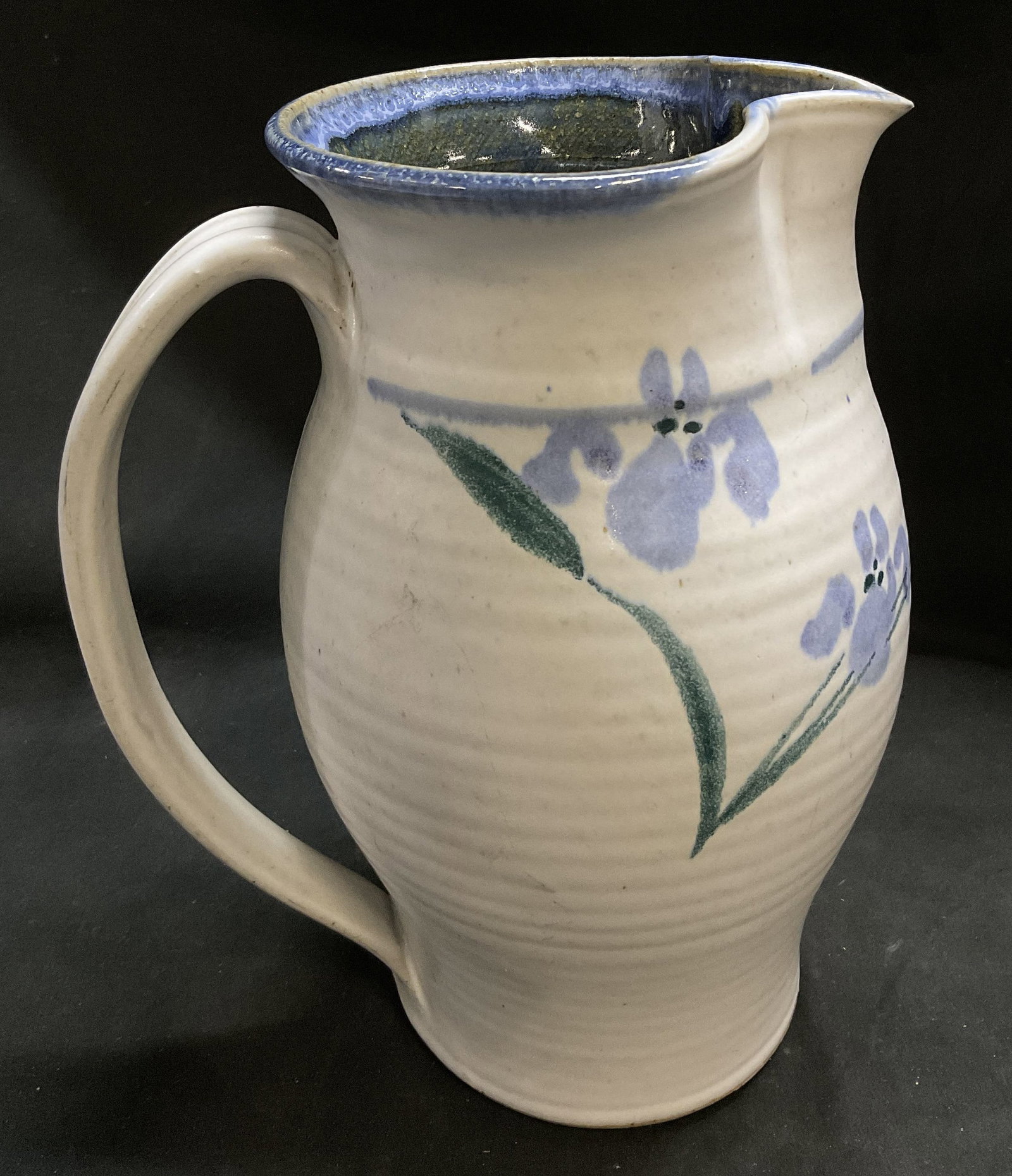 Signed Hand-Thrown Studio Pottery Pitcher: Signed Hand-Thrown Studio Pottery White Pitcher with Hand-Painted Blue Iris Pattern. Signature reads illegibly. Glossy blue glaze on outer rim. Scratching present. Condition consistent with age and ex