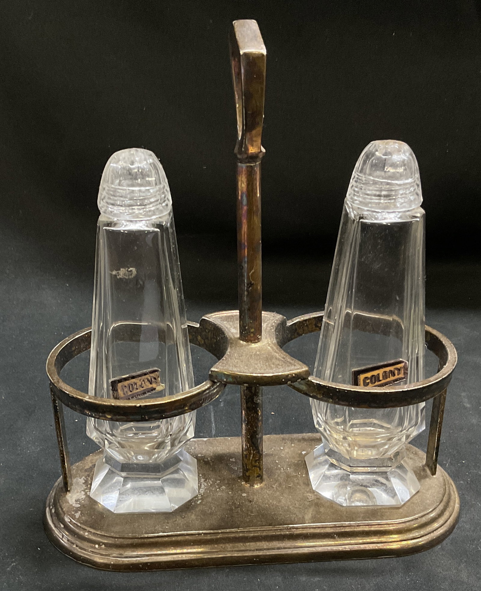 VTG Colony Glass Shakers in Int Silver Co Caddy: Vintage Colony Glass Salt and Pepper Shakers in International Silver Co Silver-Plated Caddy. Pattern 0204-01. Peeling to labels, tarnishing and aging to metal. Measures approx 7in H x 6.25in L. vintag