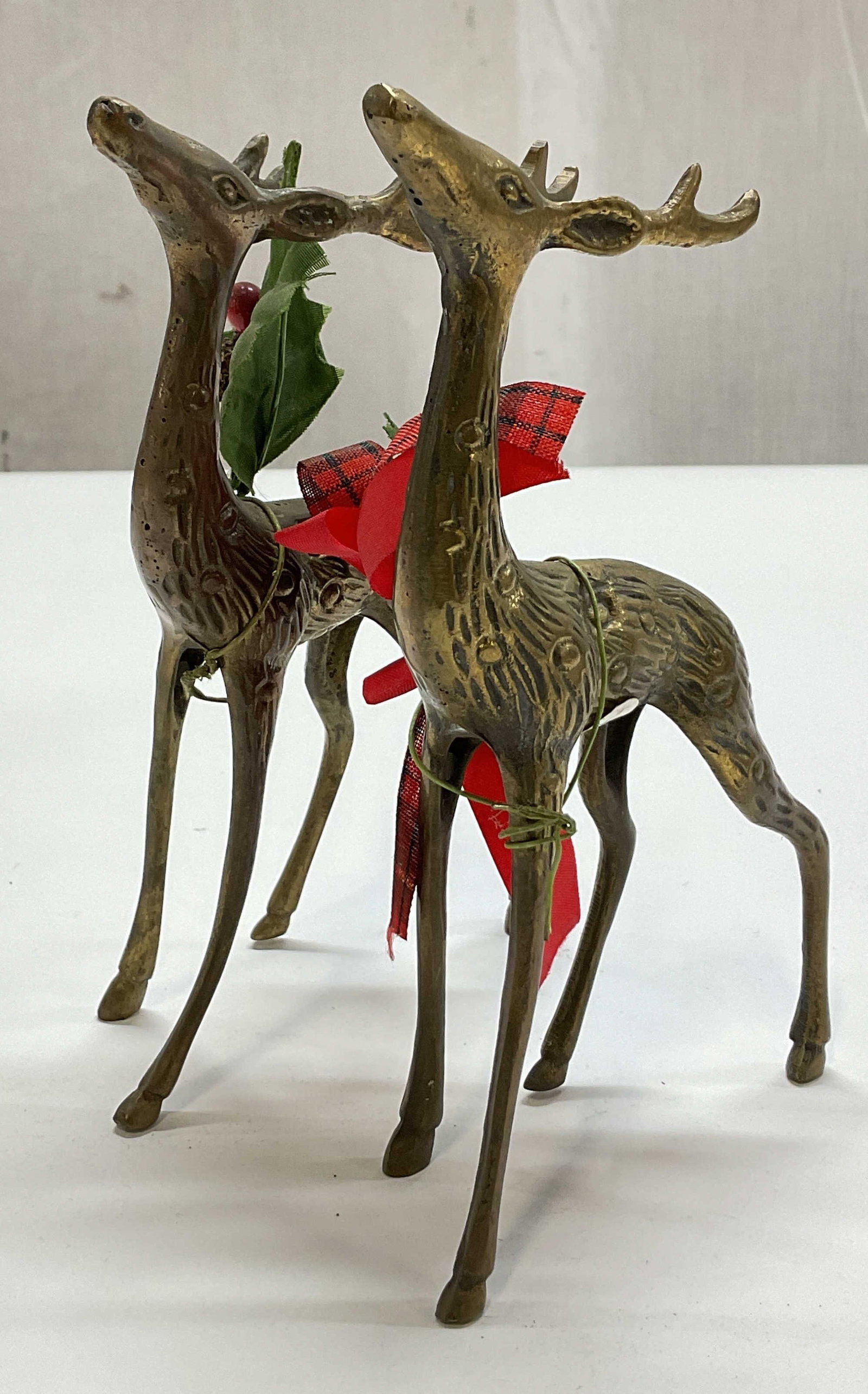 Pair MSR Imports Brass Reindeer Figurines: Pair of MSR Imports brass reindeer figurines. Detailed designs and features. Standing reindeer figures. Accented with holiday bows and holly leaves with berries. Measures approx 2 x 4 x 6 inches.