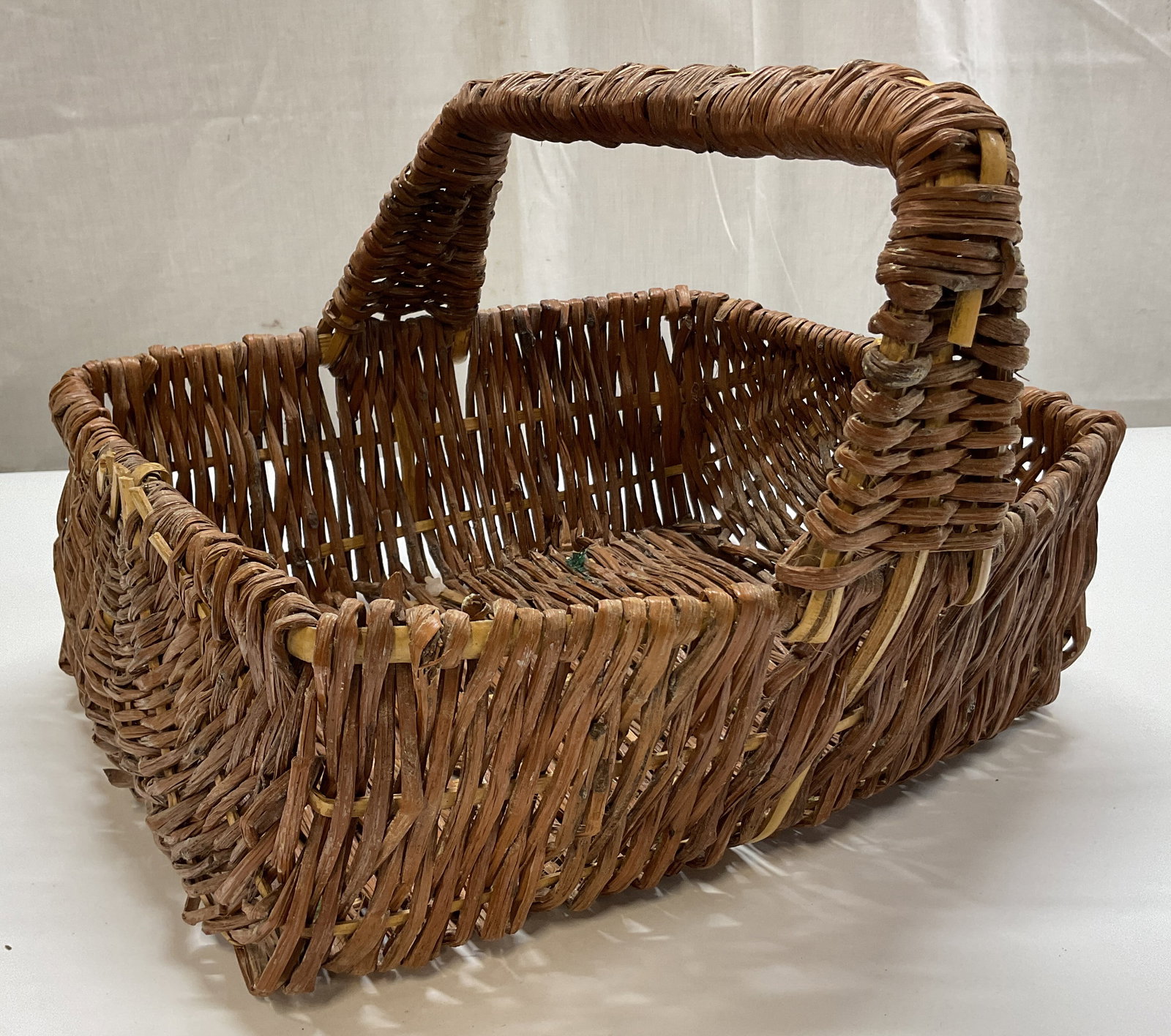 Vintage Woven Wicker Rectangular Basket: Vintage woven wicker rectangular basket. Rectangular shape. Central arched handle. Woven design. Measures approx 12 x 13 x 9 inches. Surface wear consistent with exposure. Basket, home decor, decor, h