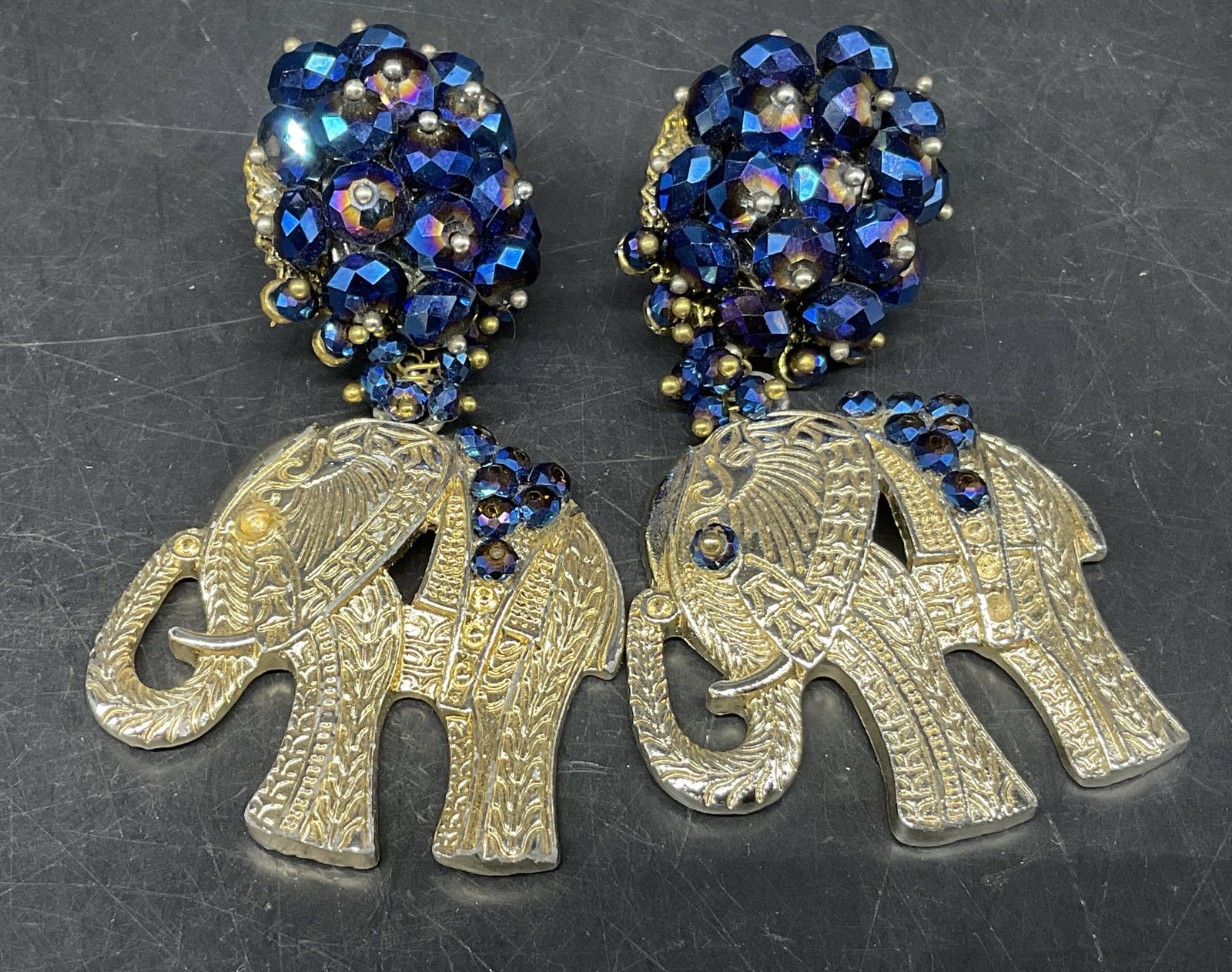 VTG Bohemian-Style Elephant Clip-On Earrings: Vintage Bohemian-Style Clip-On Earrings. Silver-Toned elephants with clustered dome of cobalt blue and Aurora Borealis rhinestones. Missing stone on eye. Measures approx 3.25in H x 1.75in L. vintage