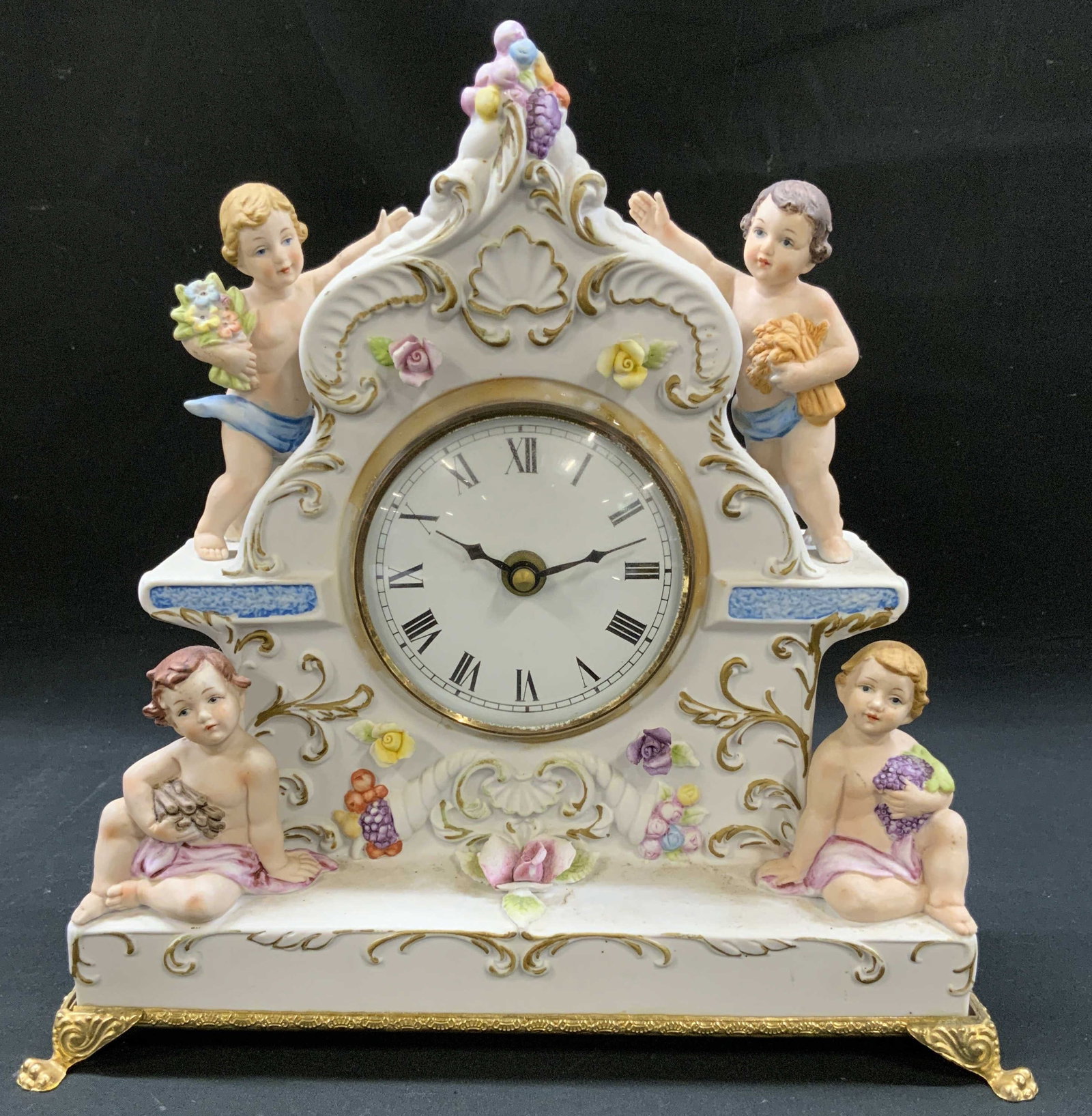 Vtg Capodimonte Four Seasons Cherub Clock, Italy: Vintage Capodimonte Italian porcelain mantel clock featuring four 3 dimensional cherubs representing the four seasons. Hand painted floral swags, scrollwork, and gold gilt accents. Clock face, black R