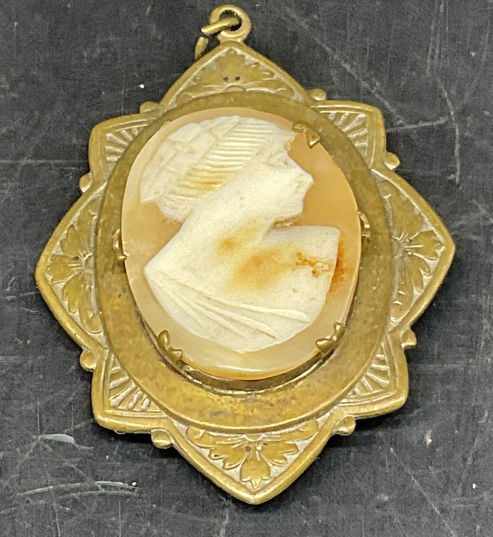 VINTAGE Carved Shell Cameo Locket Pendant: Vintage Carved Shell Cameo Locket Pendant. Cream colored portrait bust of woman with orange background. Scalloped etched brass border. Opens at the back. Tarnishing and oxidization present. Measures a