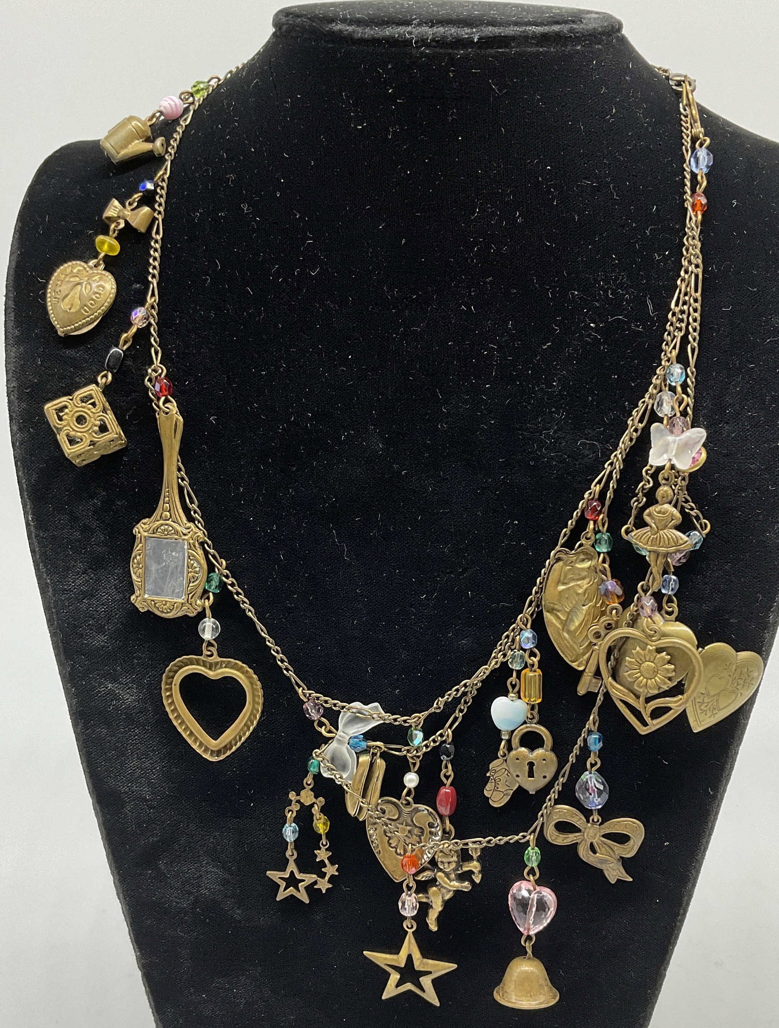 VTG-Style Brass-Plated Charm Necklace: Vintage-Style Brass-Plated Charm Necklace. Charms include cherubs, handheld mirrors, hearts, shoes, keys, watering cans and more. Glass beaded accents. Measures approx 25in L. vintage-style, brass-pla