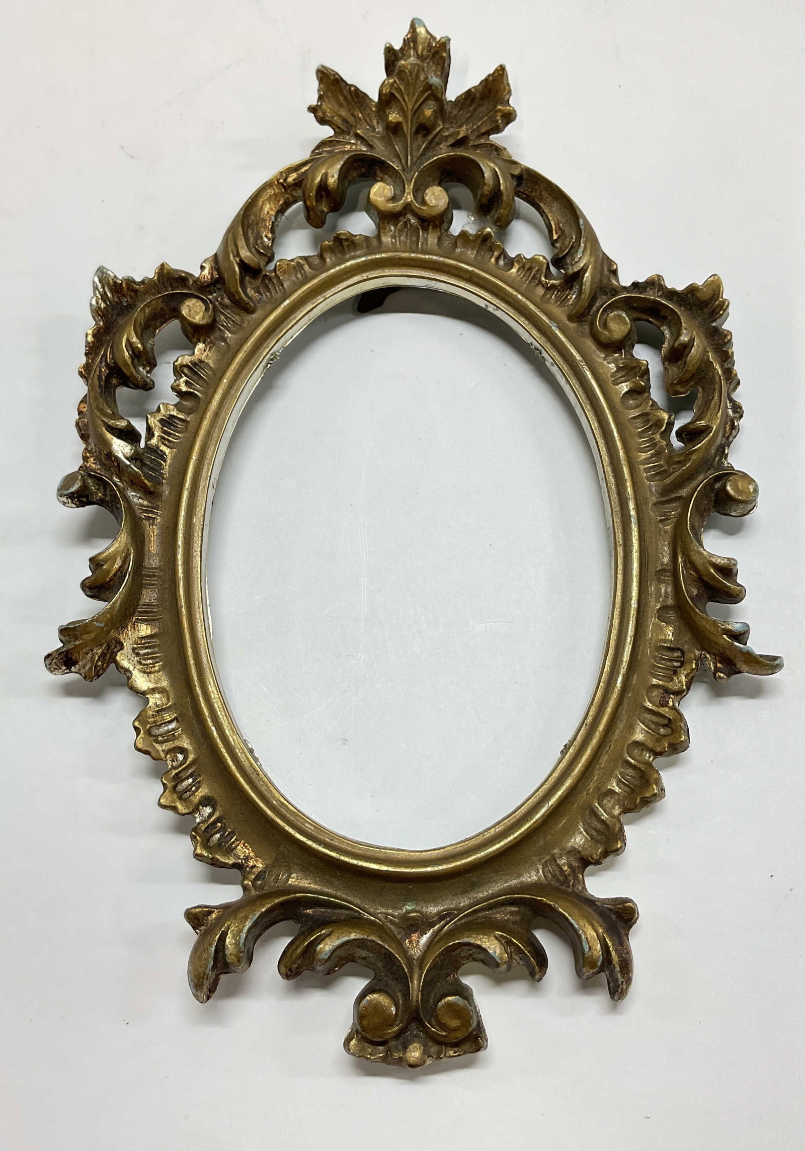 Vintage Ornate Gold Toned Resin Frame Italy: Vintage ornate gold toned resin frame. Marked made in Italy. Other markings reads illegibly. Oval shaped. Scroll and leaf motifs. Painted. Measures approx 7.5 x 11 inches. Chipping and scratching. Fra
