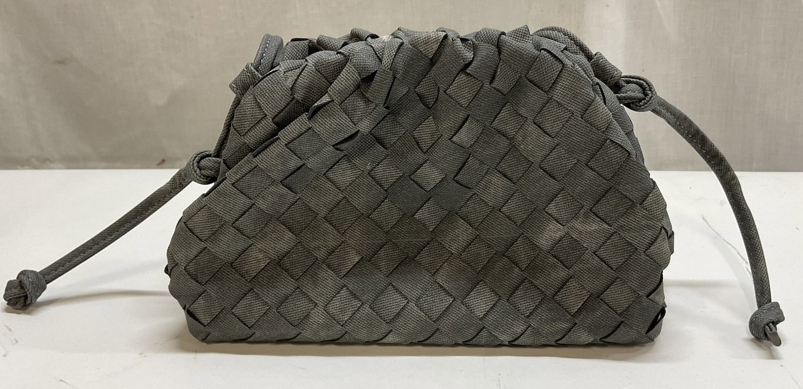 Woven Leather Style Bag: woven leather style bag, grey shoulder bag. Drawstring design, attached strap. Textured diamond like pattern. Comes in dust bag. Interior compartments. Measures approx 6 x 8 inches. Surface wear consi