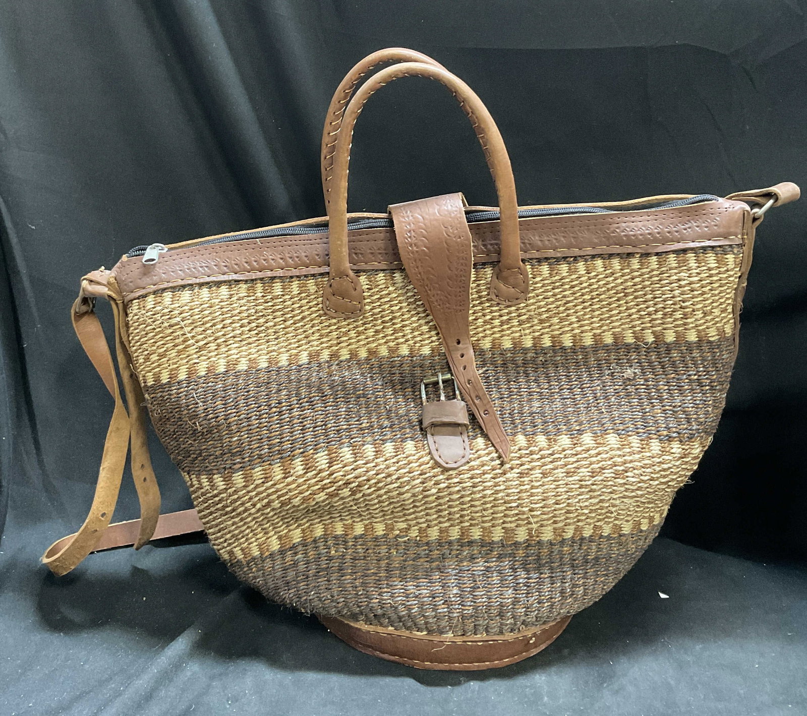 Handwoven African Kiondo Basket Bag: Handwoven African Kiondo Basket Bag. Woven with eco-friendly sisal plant fibers paired with wool or jute. Multi-Toned striped pattern. Stitched leather handles, trim, base, shoulder strap, and front b