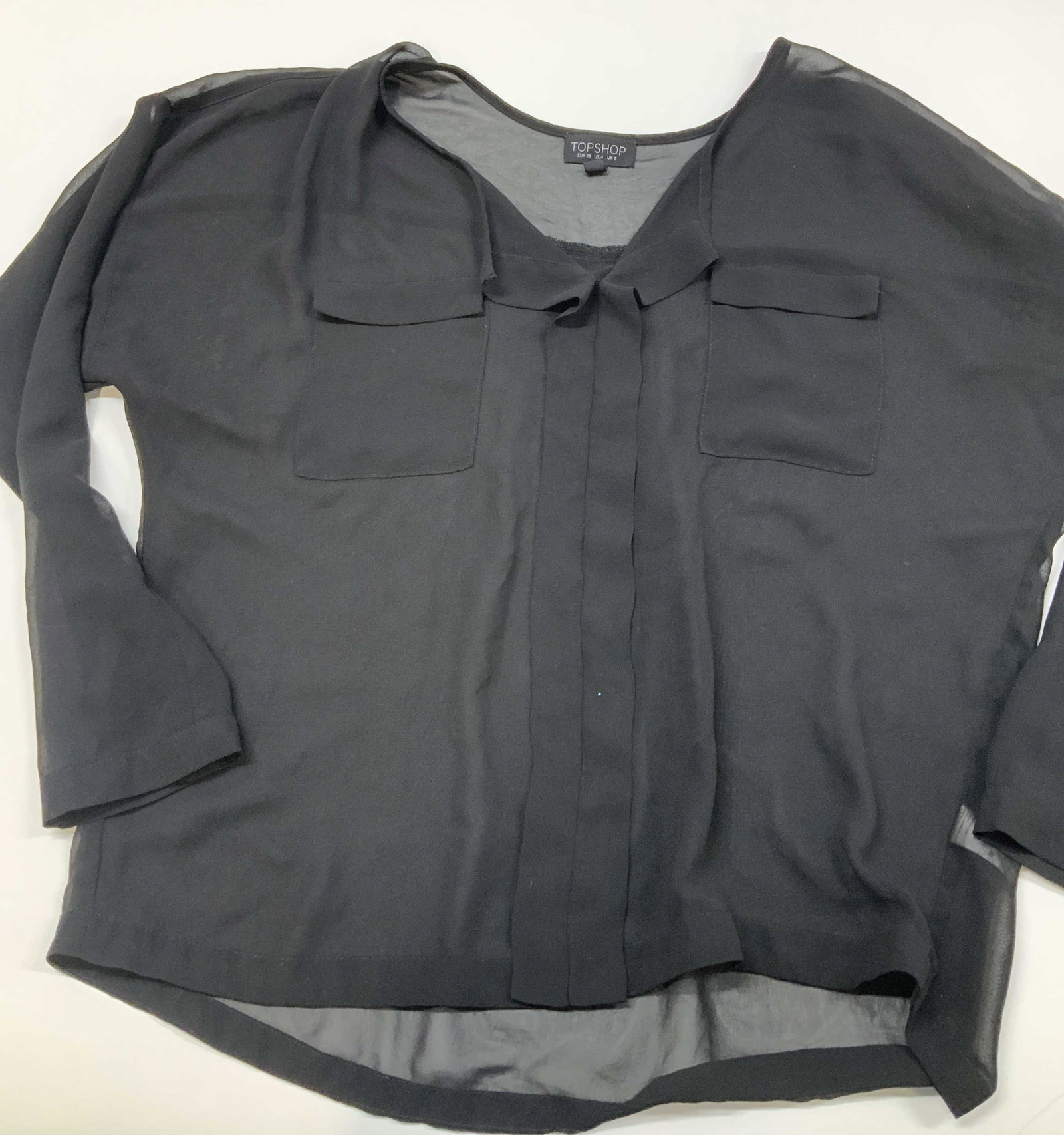 TOP SHOP sheer utility style blouse, Romania: TOP SHOP sheer utility style blouse. Made in Romania form 100% polyester in size 4. The front features two symmetrical vertical center flaps extended from the collar. It also has button cuffs and 2 ch