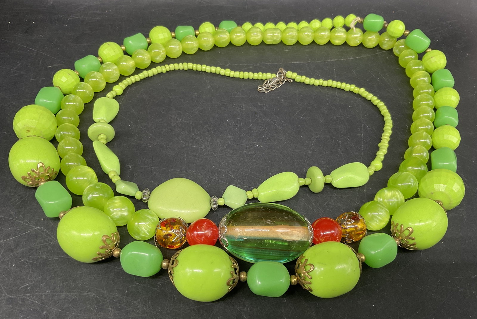 Lt3 60s-Style Lime Green Beaded Necklaces: 3 1960s Style Lime Green Beaded Necklaces. Includes small multi-shades of green in various shapes necklace, a swirled green necklace with large clear beaded accents, and a larger multi-shades of green