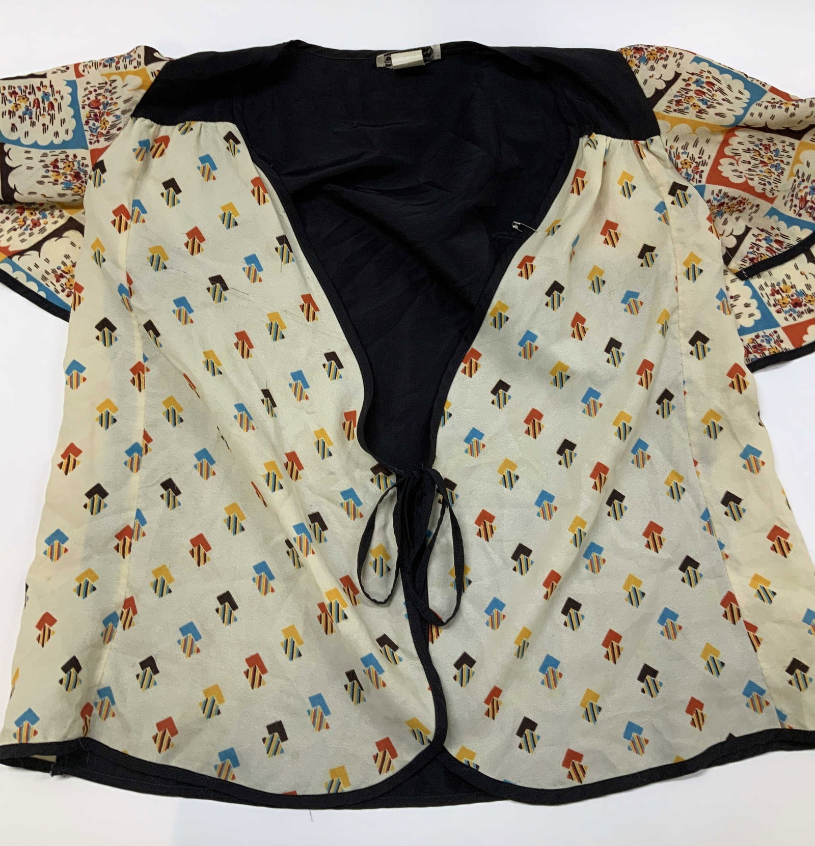Vintg Trafalgar Square tie front blouse: Vintage Trafalgar Square tie front blouse. The main design features a cream base decorated with colorful repeating diamond shapes. The wide sleeve s display a multicolored contrasting abstract print.