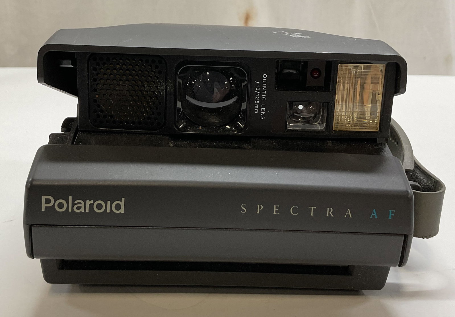 Polaroid Spectra AF Instant Film Camera UK: Polaroid Spectra AF instant film camera. Underside marked made in UK. Quintic lens f10 125mm. Collapsible body with attached strap. Measures approx 5.5 x 6.5 x 3.5 inches. Not tested for function, sol