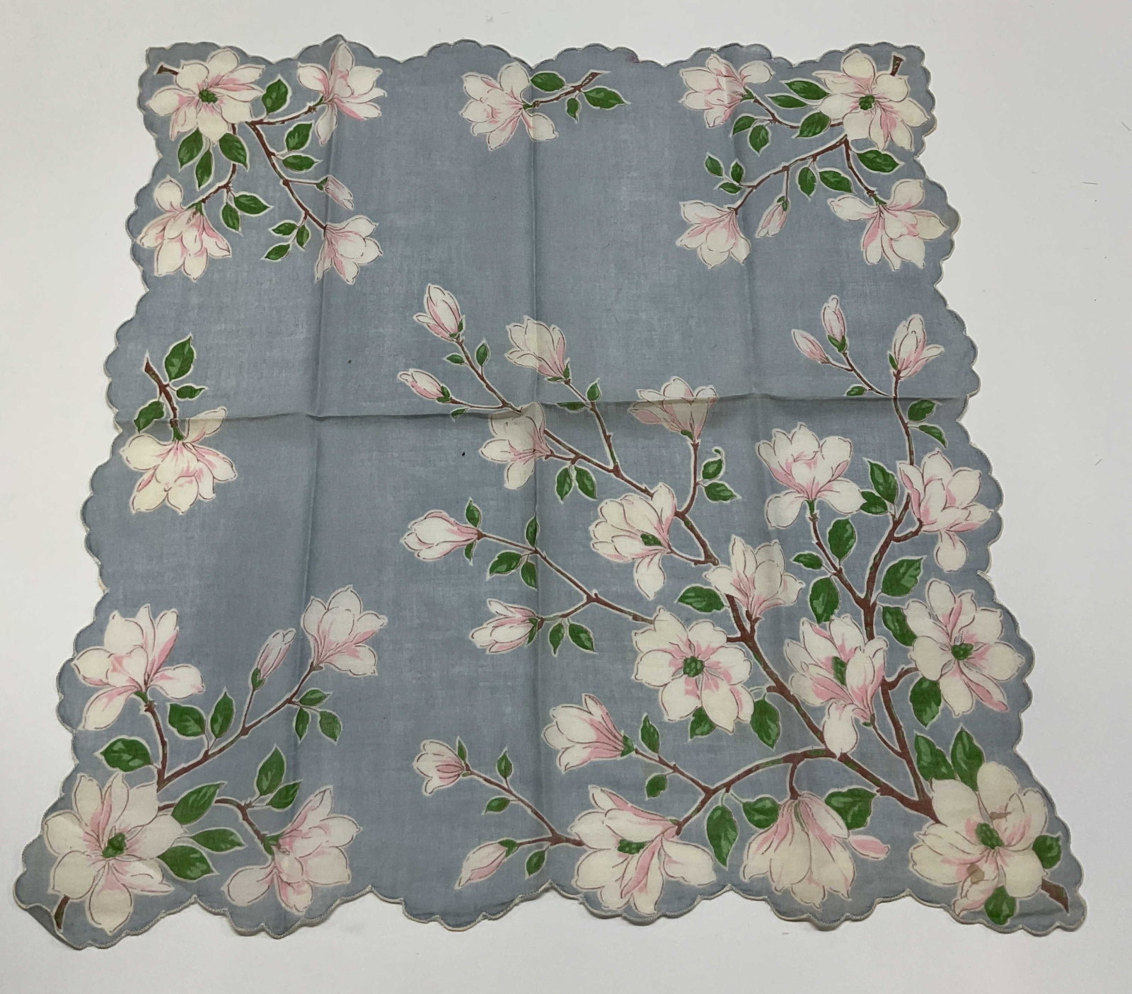 Vintage Scalloped Floral Linen Napkin: Vintage scalloped floral linen napkin. White scalloped trim. Light blue background with floral motifs in pink, white, green, and brown. Measures approx 15.5 x 16 inches. Blemishes. Napkin, linens, tab