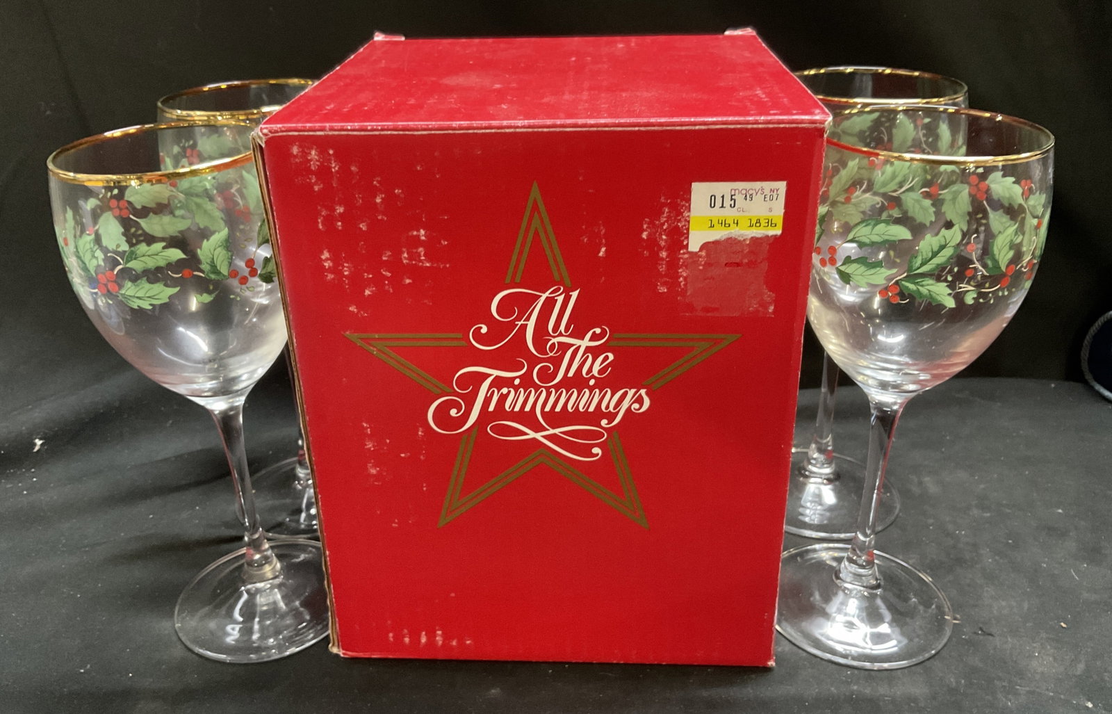 1986 OB Macys All the Trimmings Wine Glasses: Vintage 1986 Set of 4 Macys All the Trimmings Holiday Collection Wine Glasses in Original Box. Holly pattern. Gilt rims. Some finish loss. Measures approx 8.25in H x in L x in W x 3in Diam. vintage wi