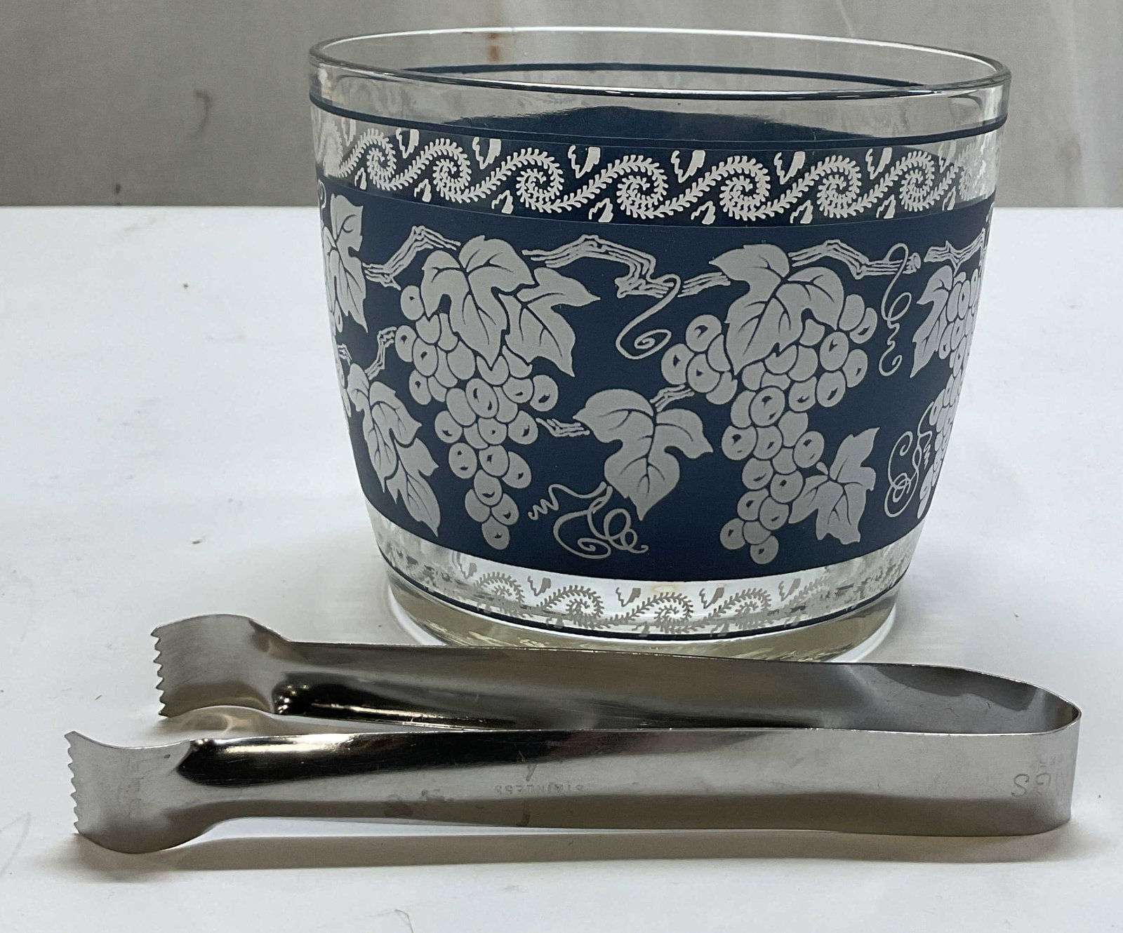 Hazel Atlas Blue&White Grapevine Glass Ice Bucket: Hazel Atlas blue and white grapevine glass ice bucket. Marked on underside. Blue and white grapevine pattern with scroll motifs. Comes with stainless steel ice tongs, marked Pom Tongs Stainless.