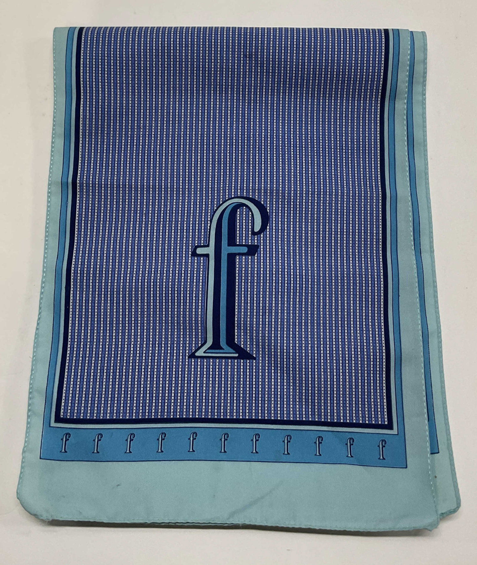 Vintage Blue Monogram Silk Scarf: Vintage blue monogram silk scarf. Ornate F monogram design. Varying shades of blue, geometric pattern. Measures approx 10 x 52 inches. Blemishes. Scarf, silk scarf, wearables, clothing, outerwear,