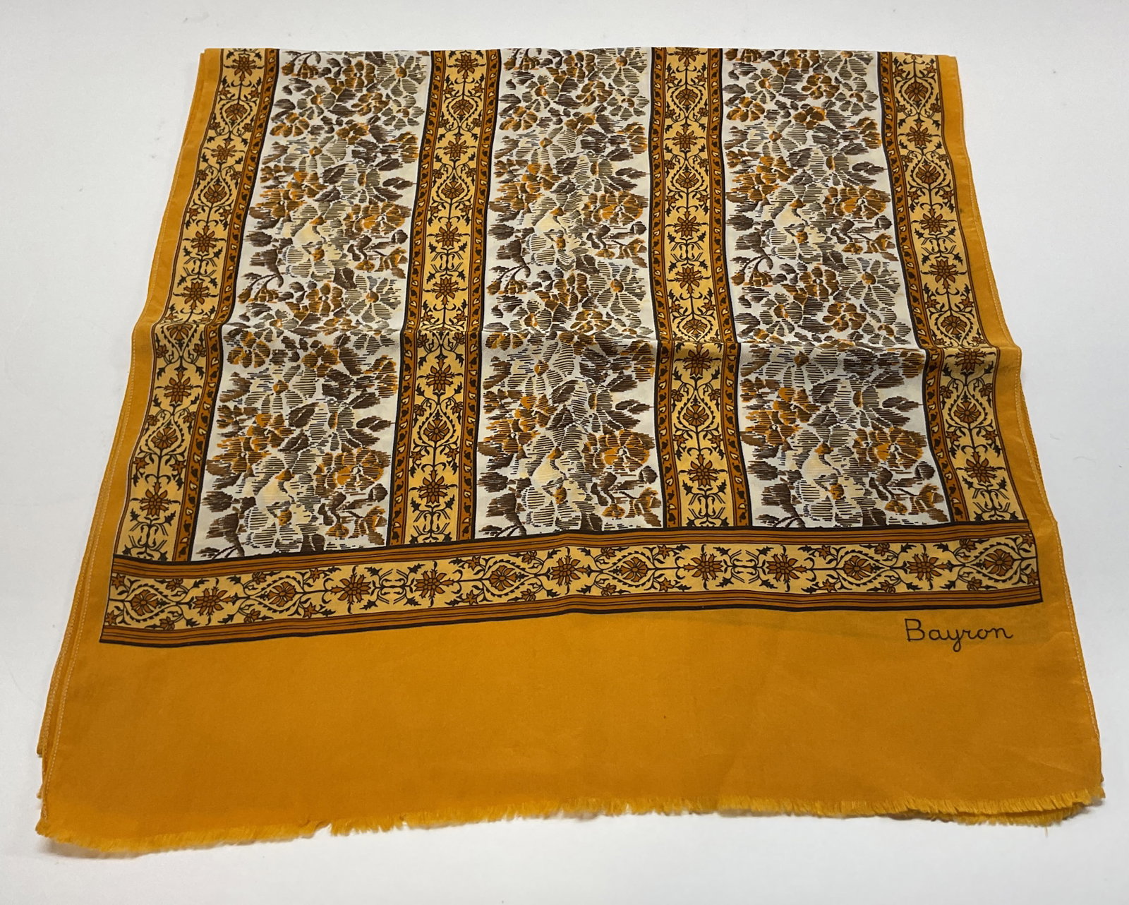 Bayron Yellow Floral Fringed Silk Scarf: Bayron yellow floral fringed silk scarf. Marked Bayron. Yellow fringed trim. Floral motifs in varying colors. Measures approx 13.5 x 56 inches. Wear consistent with exposure. Scarf, silk scarf,