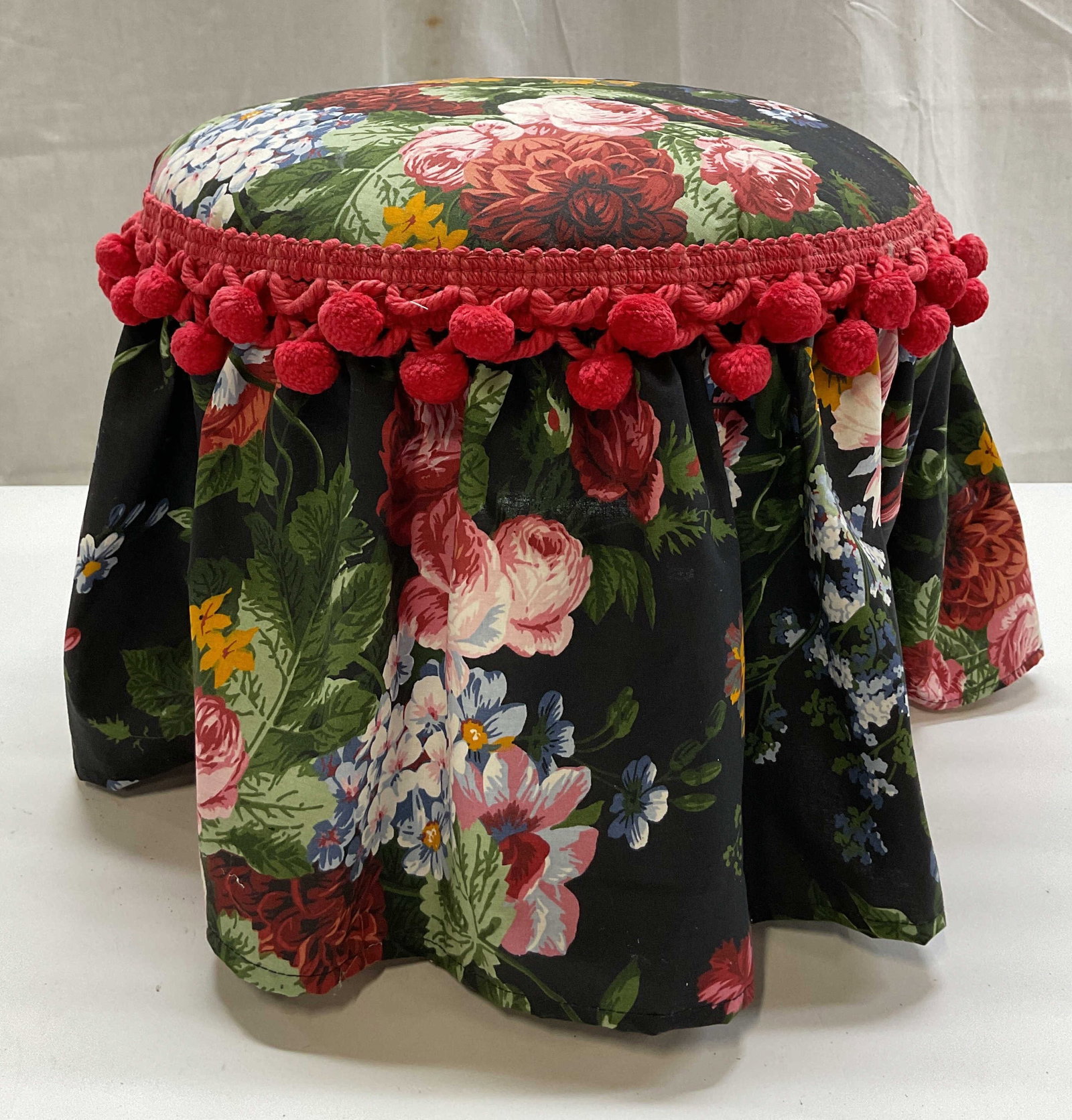 Ralph Lauren Fabric Wooden Vanity Stool: Ralph Lauren fabric wooden vanity stool. Three wooden legs. Round top. Upholstered Ralph Lauren floral fabric. Red Pom Pom trim. Varying colors. Measures ht approx 9.5 inches diam approx 12.5 inches. 