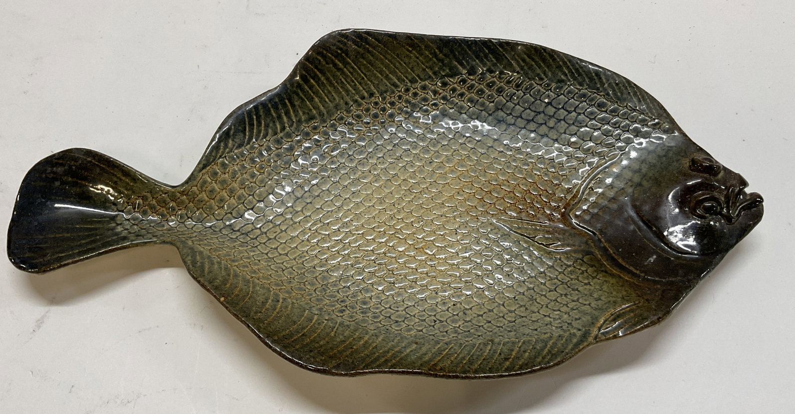 Vtg Nadeau Ceramic Flounder Fish Wall Art: Vintage Nadeau ceramic flounder fish wall art. Marked on underside, reads Nadeau, rest reads illegible. Fish shaped. Textured details and features. Light and dark tones. Glossy finish. Measures