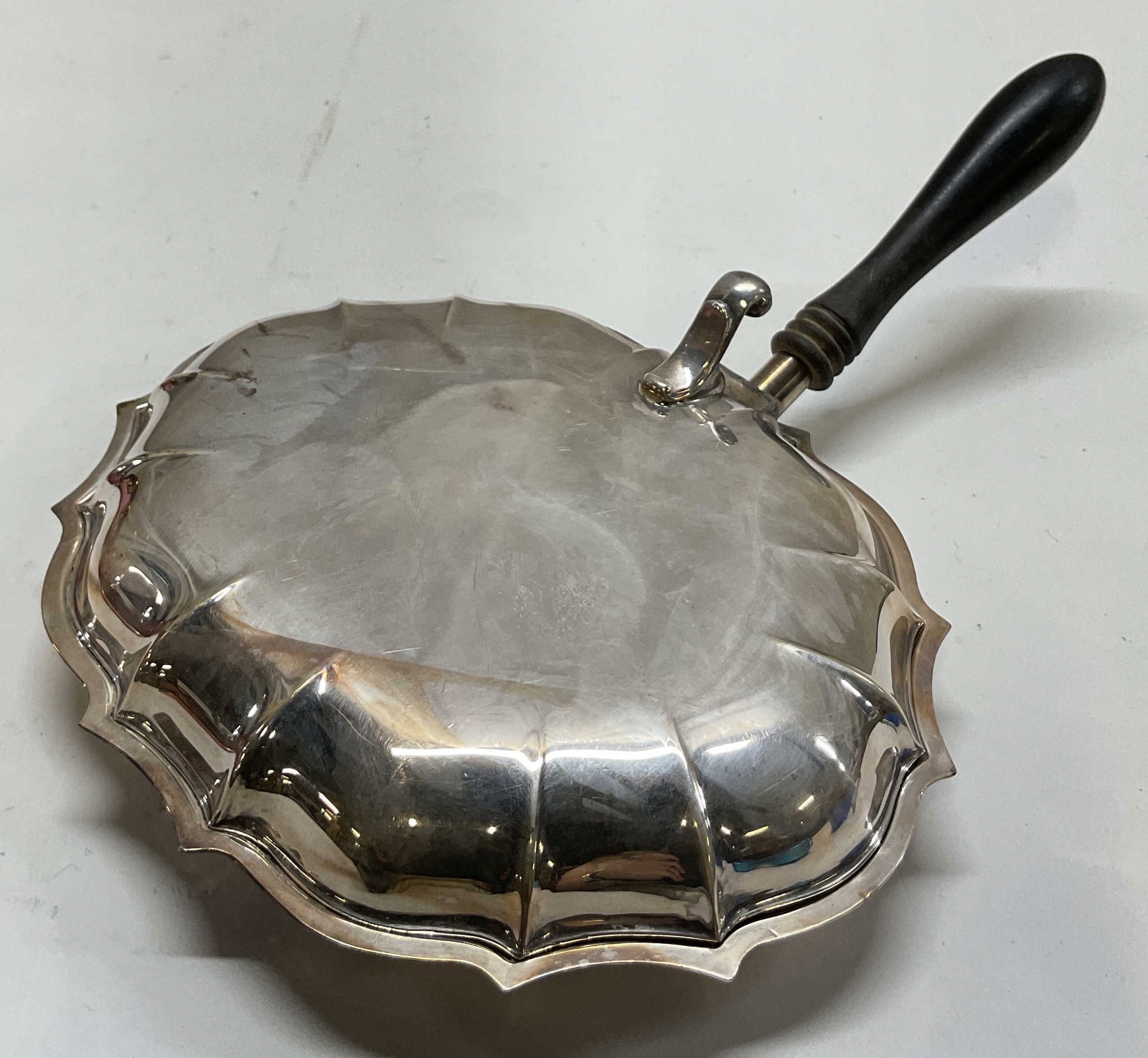 Chippendale International Silver Co Silent Butler: Chippendale International Silver Company silver plated silent butler/crumb tray. Marked on underside, reads Chippendale International Silver Company. Dark wooden handle. Scalloped Chippendale edge.