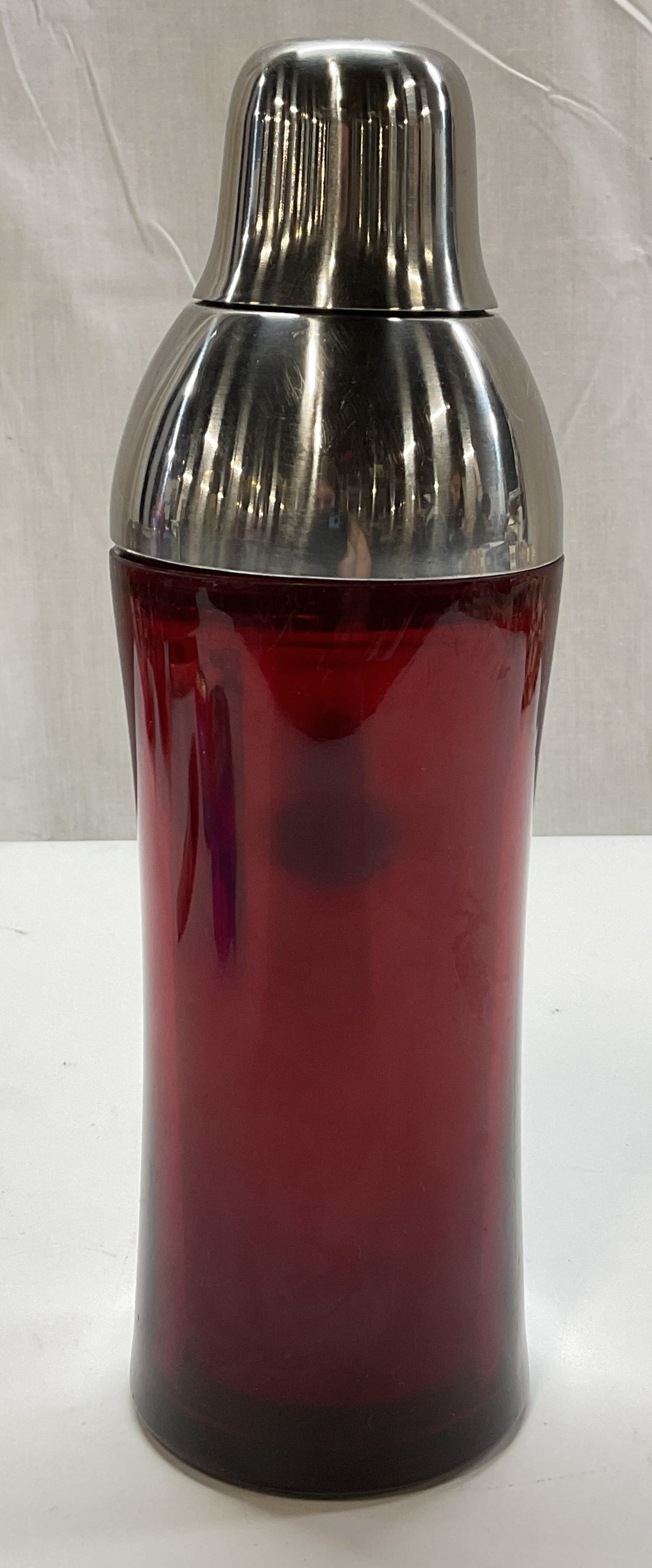 Wovo Ruby Red Stainless Steel Cocktail Shaker: Wovo ruby red stainless steel cocktail shaker. Marked Wovo on underside. Ruby red body. Stainless steel top and matching cap. Measures ht approx 10 inches diam approx 3 inches. Scratching and surface 
