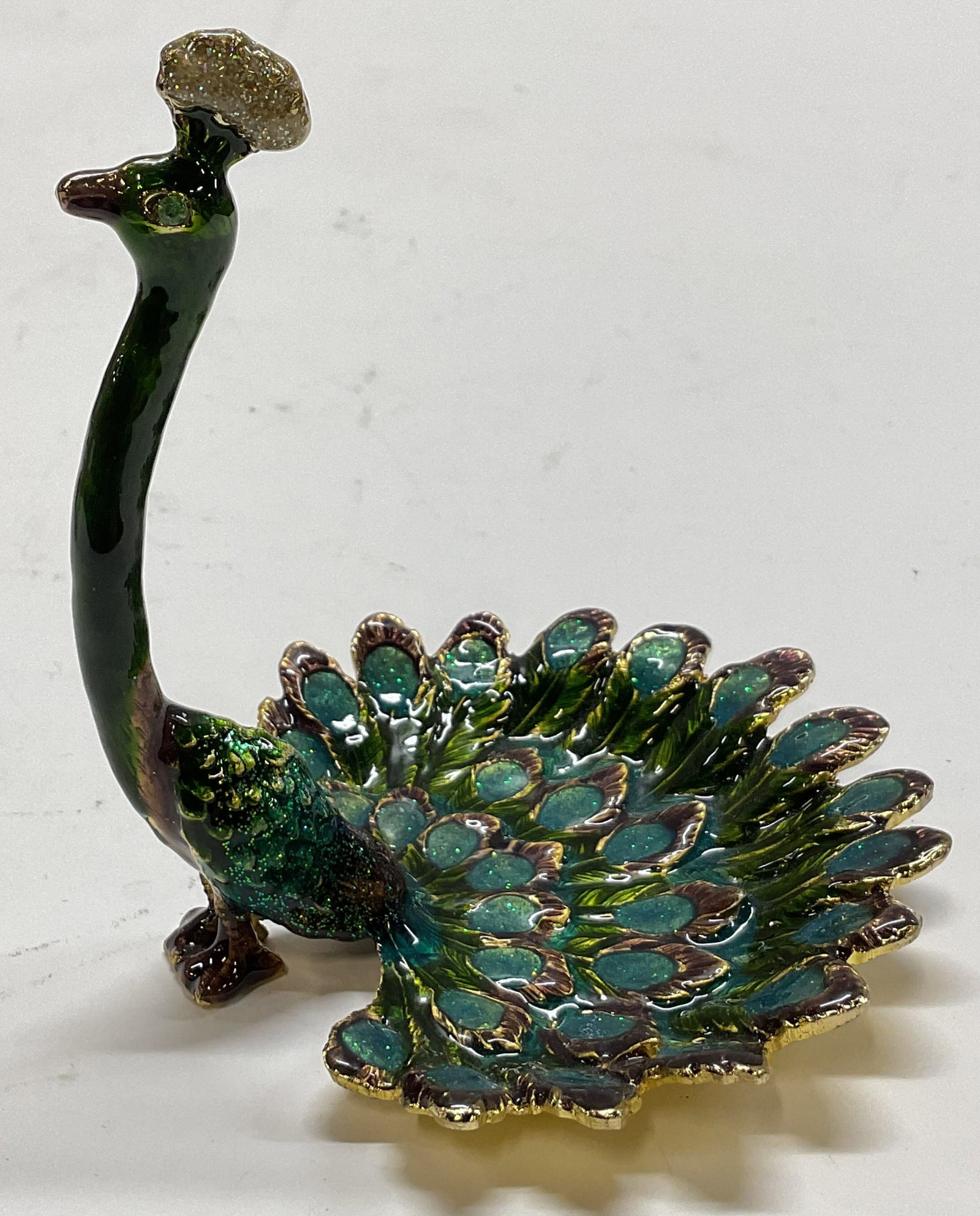 Vtg Enameled Metal Peacock Jewelry Trinket Dish: Vintage enameled metal peacock jewelry trinket dish. Scalloped edge. Peacock figure with decorative feathers. Textured details and features. Green, blue, and purple with gilt accents. Measures approx 