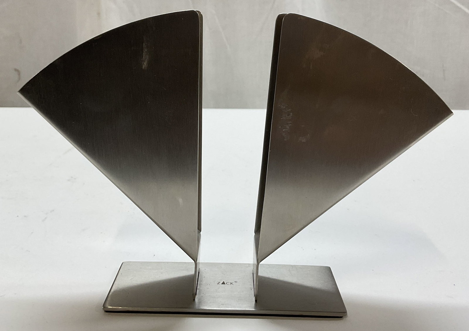 Zack Stainless Steel Triangle Shaped Napkin Holder: Zack stainless steel triangle shaped napkin holder. Marked Zack on surface. Rectangular base. Two upright triangle shaped panels. Measures approx 2 x 5 x 6 inches. Scratching. Napkin holder, Zack, hom