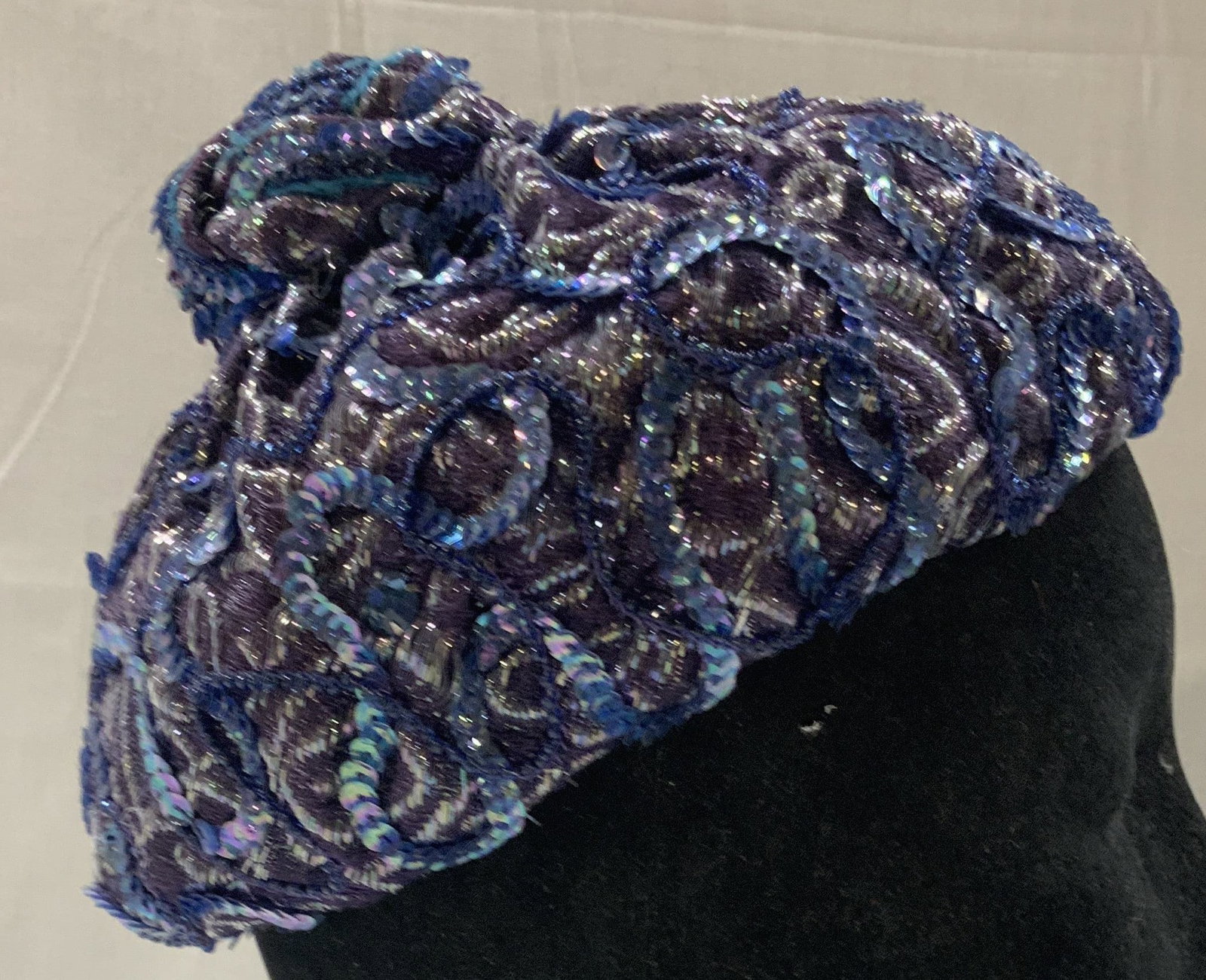 Vntg Pollyanna textured toque hat: Vinatge Pollyanna textured toque hat. Manufactured by AMY NEW YORK and sold by the brand POLLYANNA. hat features a blue and purple sequin design with gives it a textured look and feel. It has a knotte
