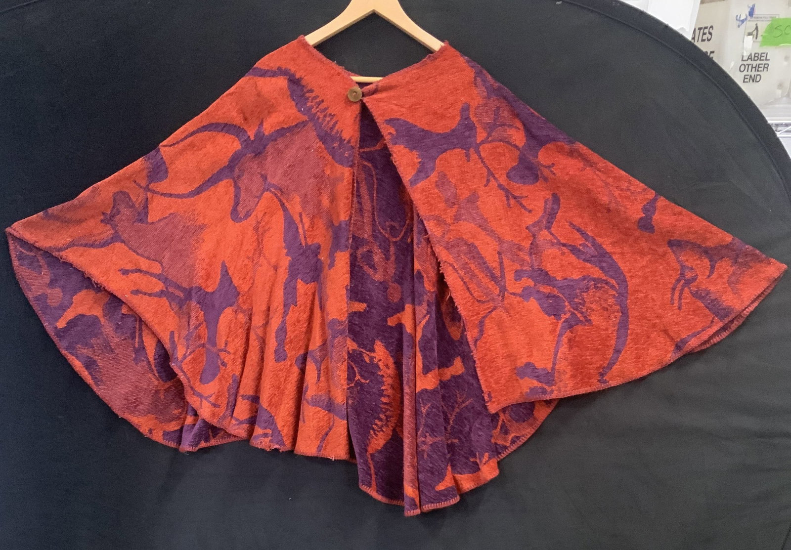 Vntg orange and purple wrap poncho: Vintage orange and purple wrap poncho. The textile features detailed silhouettes of wildlife and tree branches. The pattern is shelved through a jacquard knit process where thud colors invert in the