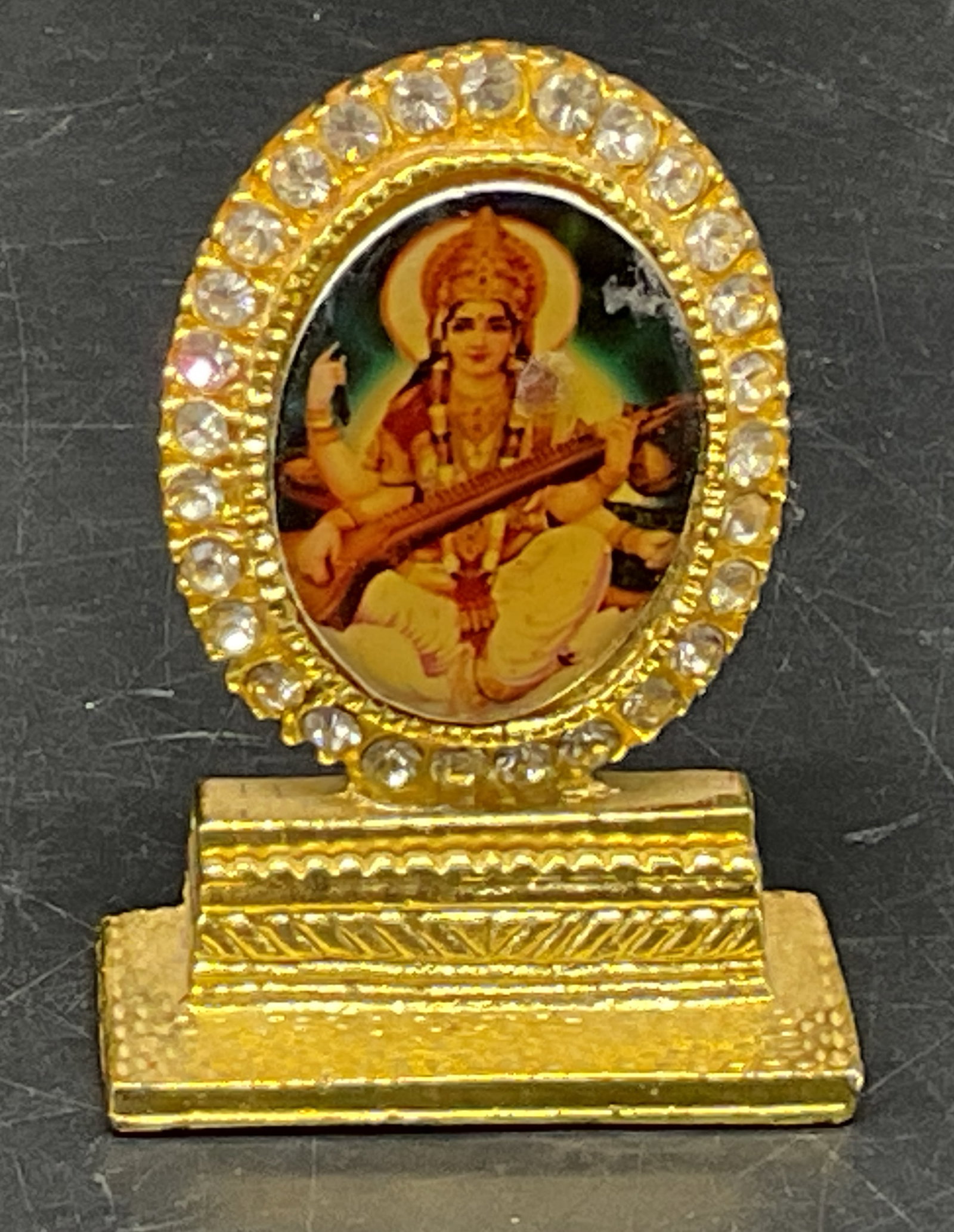 Hindu Goddess Gold-Toned Miniature Frame: Gold-Toned Miniature Oval Frame With Hindu Goddess Artwork. Framed by white rhinestones. Scratching on image. Measures app 2in H x 1.5in L. gold-toned, miniature frame, metal, Hindu Goddess,